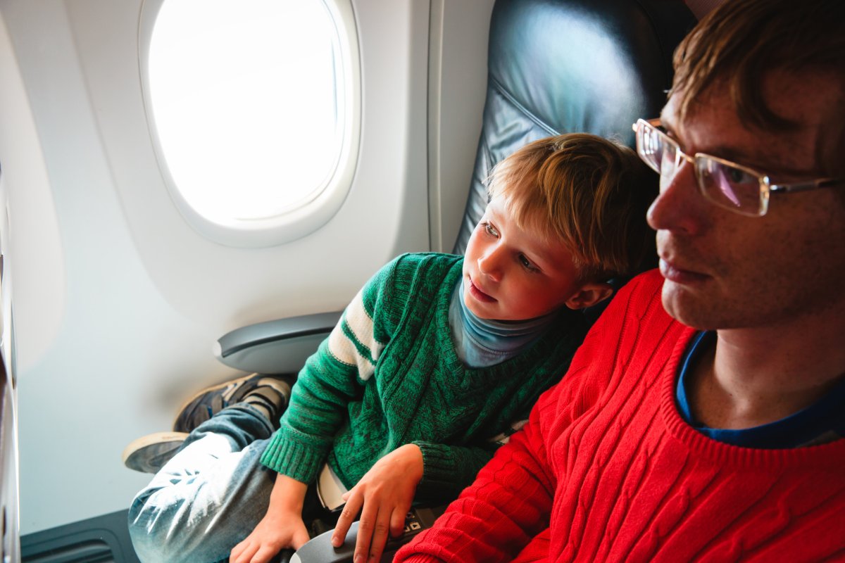 Boy sitting next to man on plane.