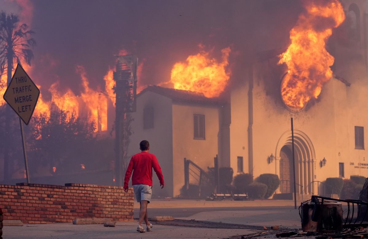 man walks in front of burning church