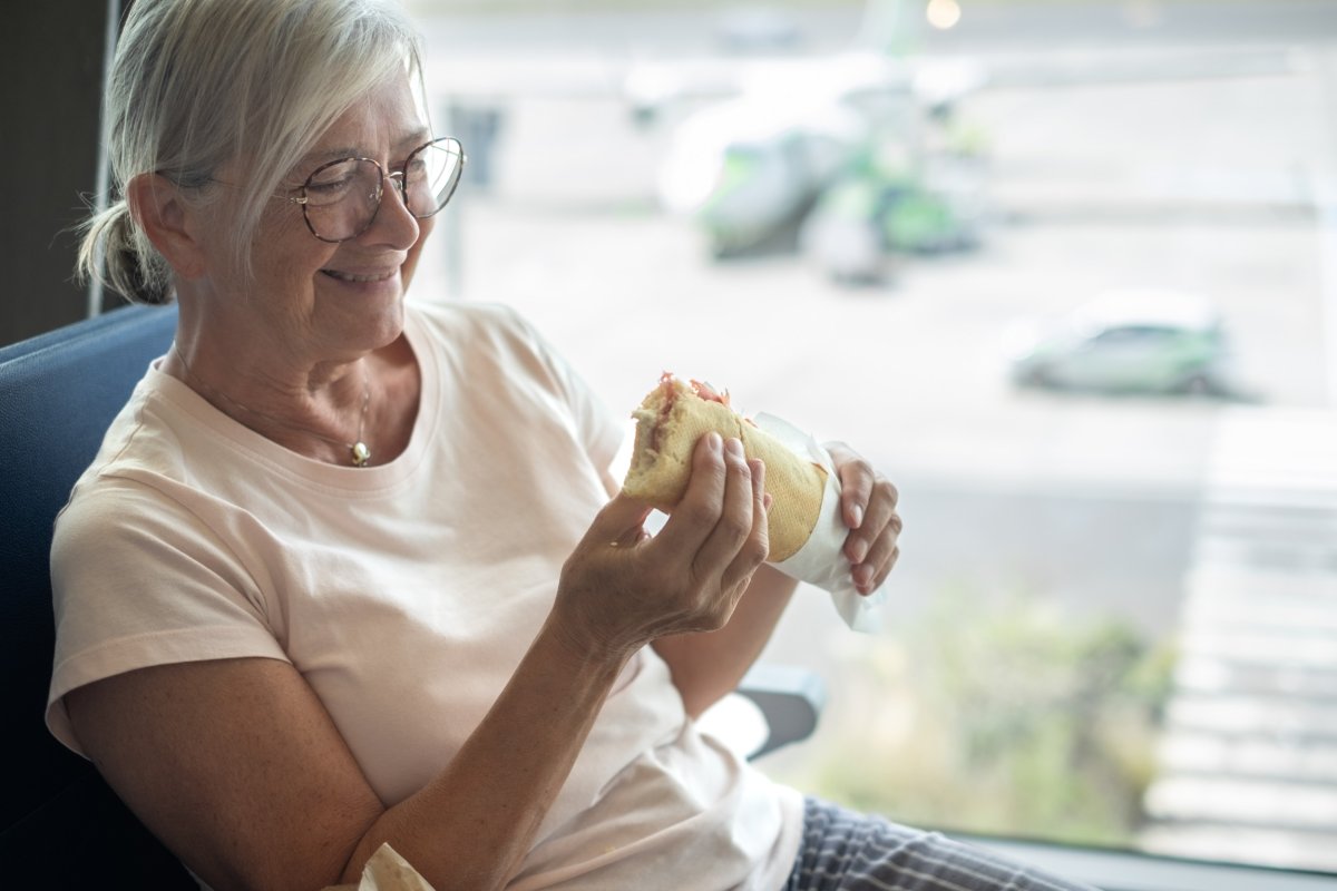 Elderly woman holding sandwich