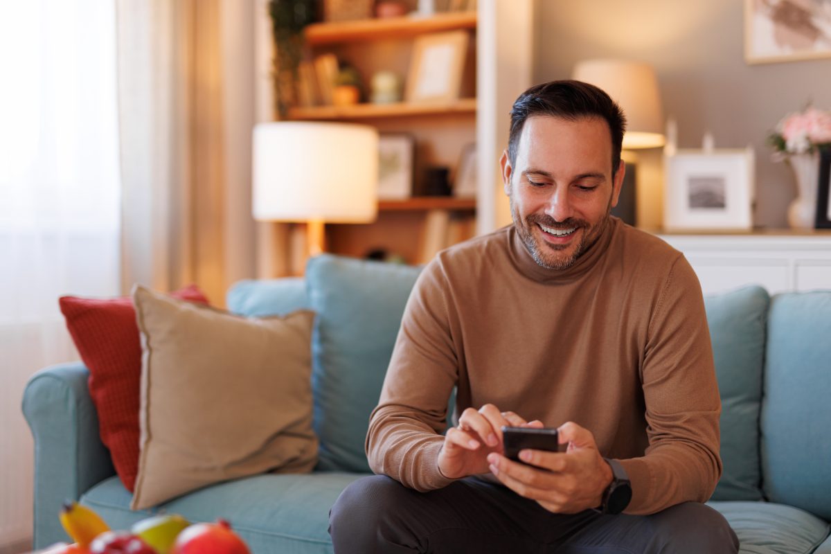 Man Blue Couch Smiles Holding Cell Phone