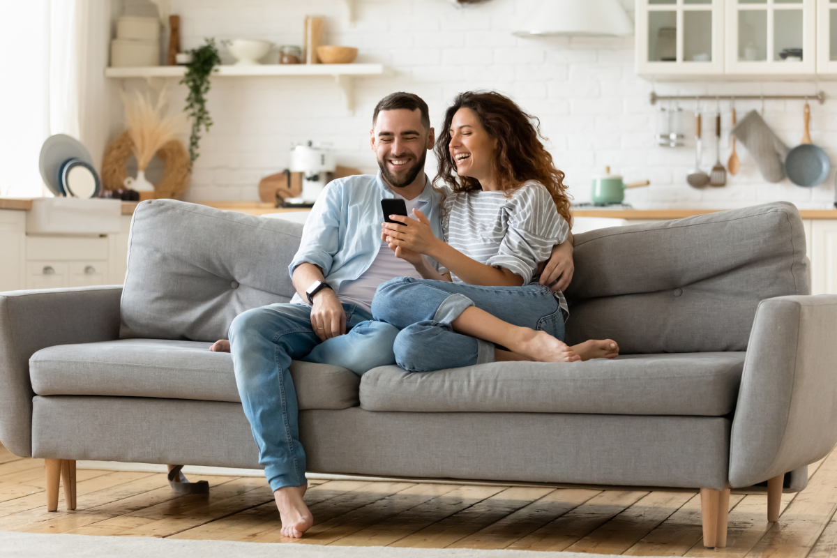 Happy Couple Smiles Couch Using Mobile Phone