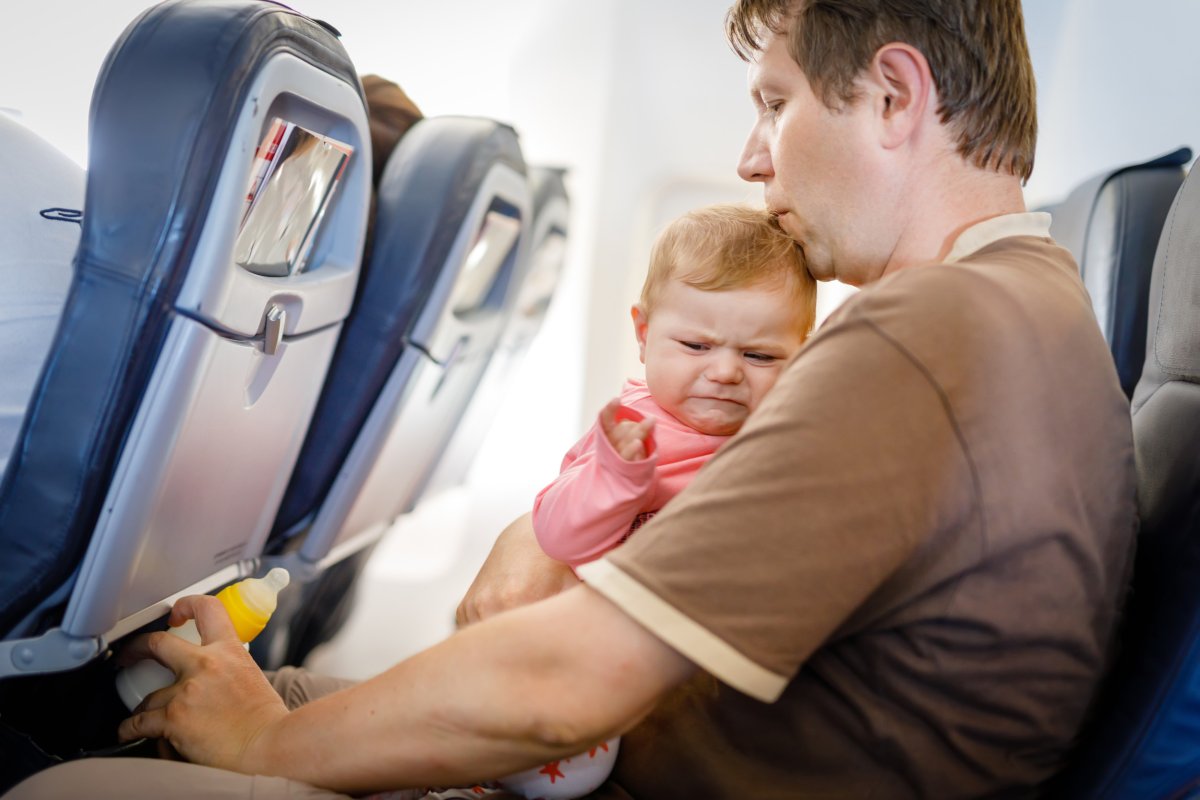 Man holding crying baby on plane.