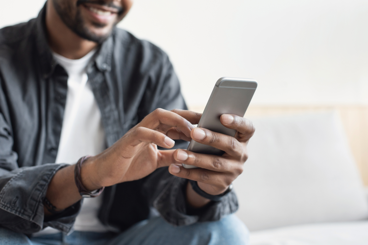 Man Wearing Jeans Button-Down Smiles Mobile Phone