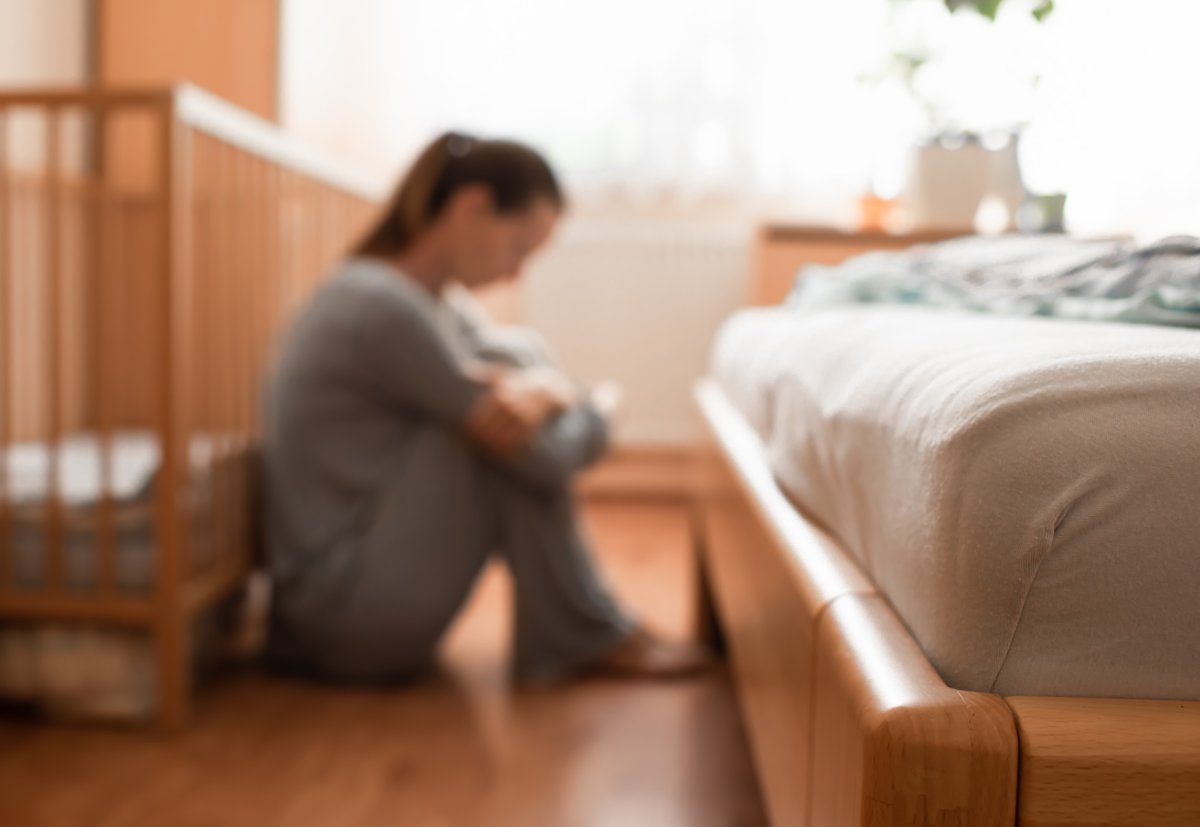 sad and tired mother by cot