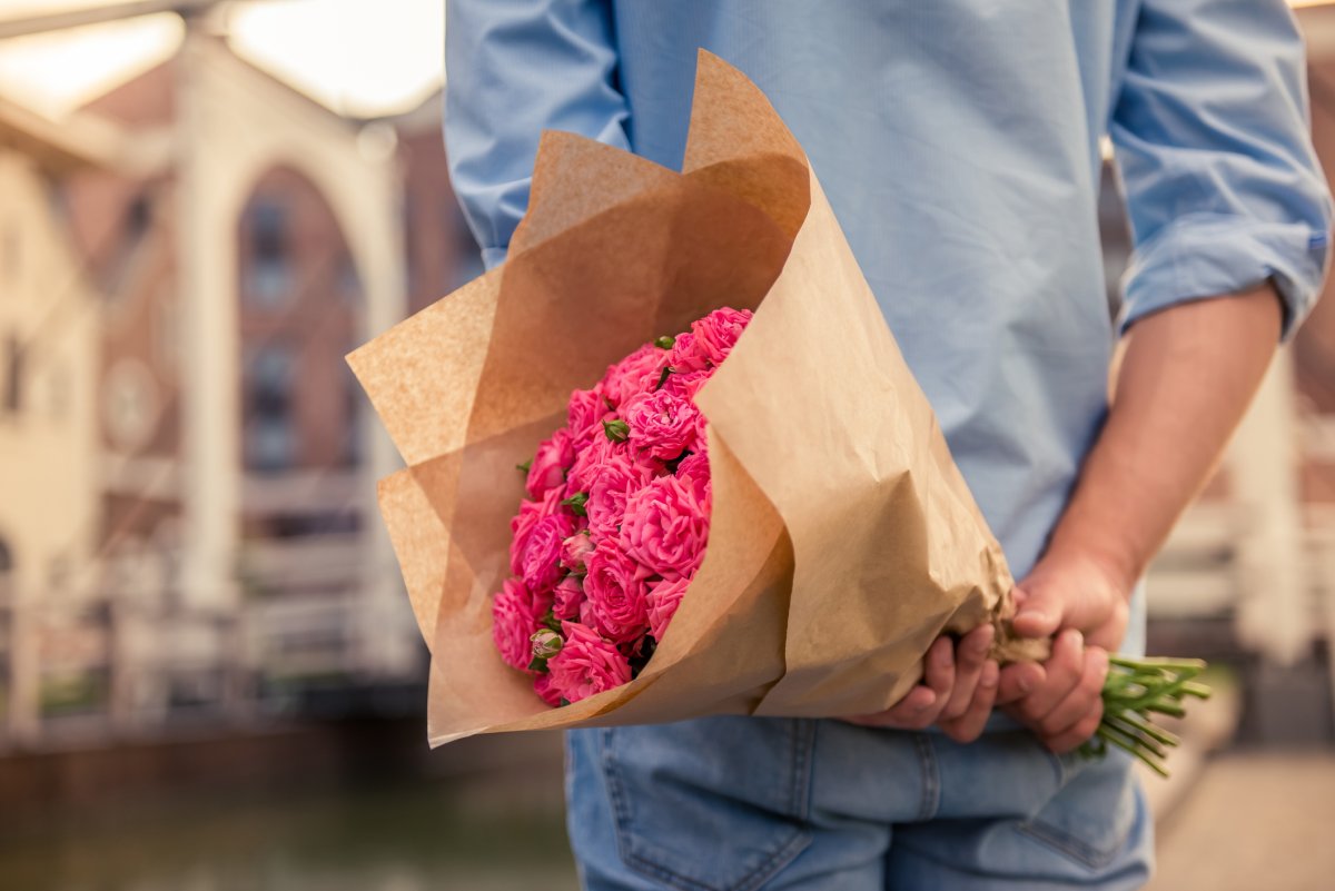 A man holds flowers behind his back