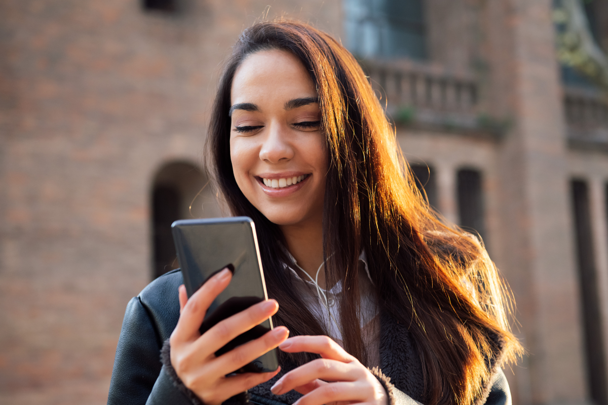Woman Long Hair Smiles Mobile Phone Street