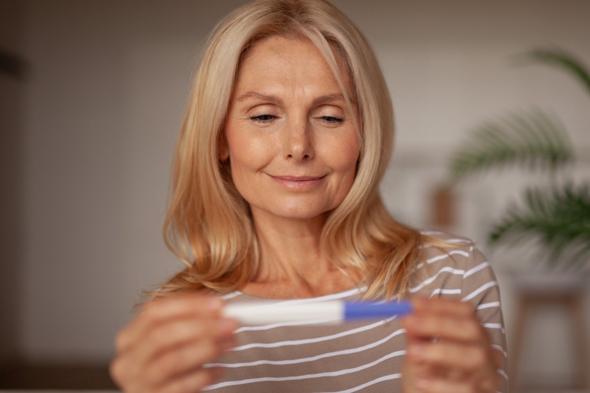 A woman looks at a positive pregnancy