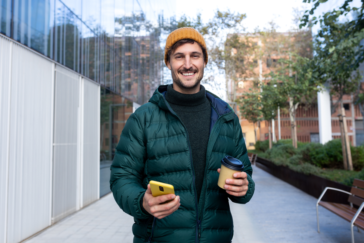 Man Green Coat Yellow Hat Phone Coffee