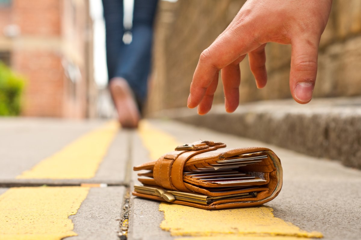 Hand reaching for wallet on street.