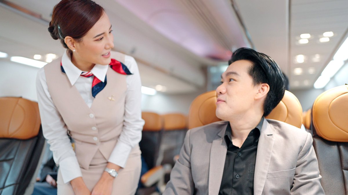 Flight attendant speaking to passenger.