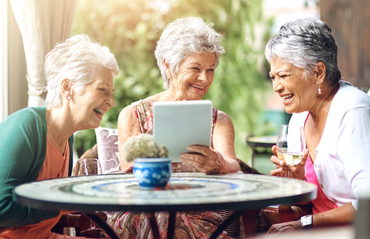 Three older women laughing at a table.