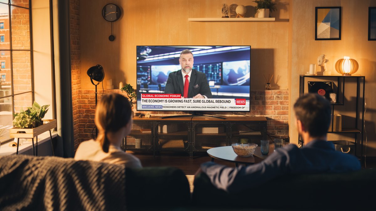 A couple watches a news broadcast