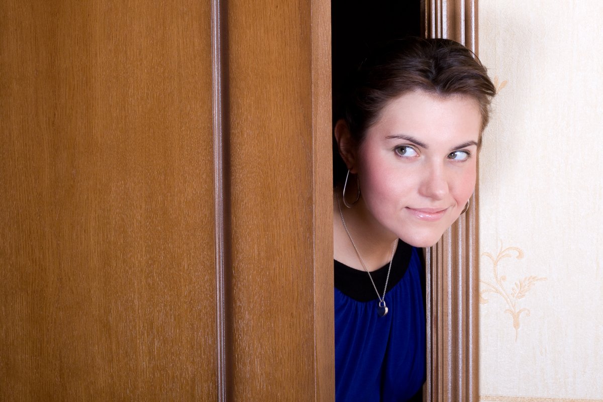 Woman peeking out from behind door.