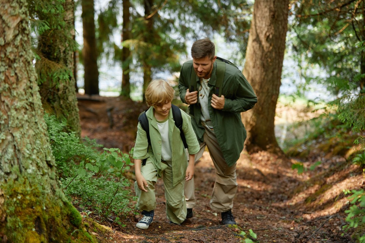 Man and child hike in the woods.