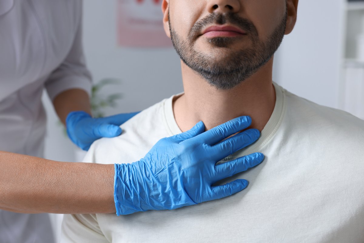 Endocrinologist examining thyroid gland of patient at