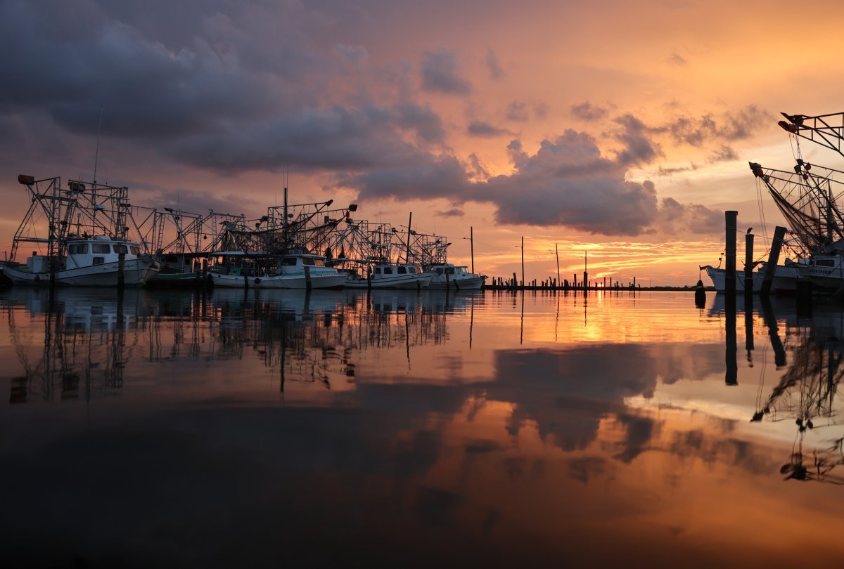 The sun sets beyond shrimp boats