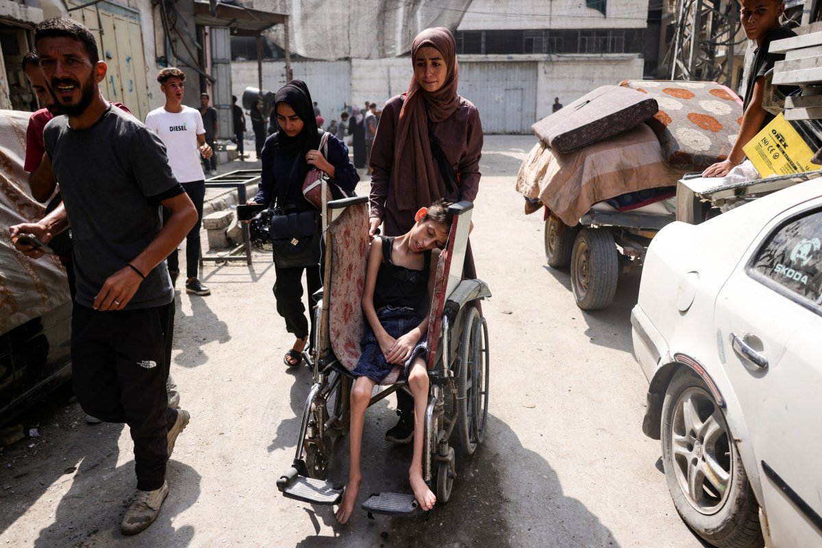 Palestinian woman pushes a child's wheelchair 