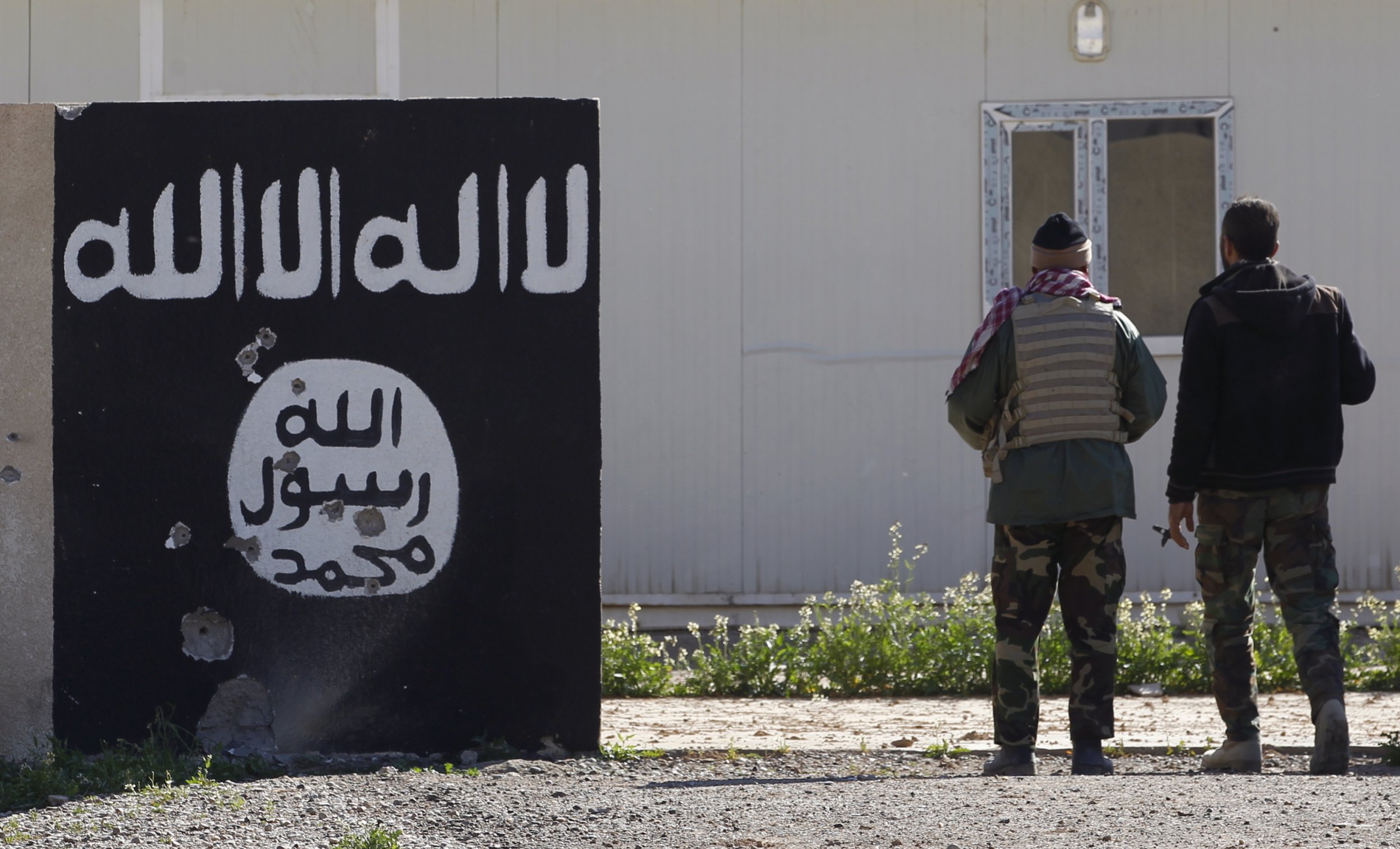 Shi'ite fighters stand near a wall