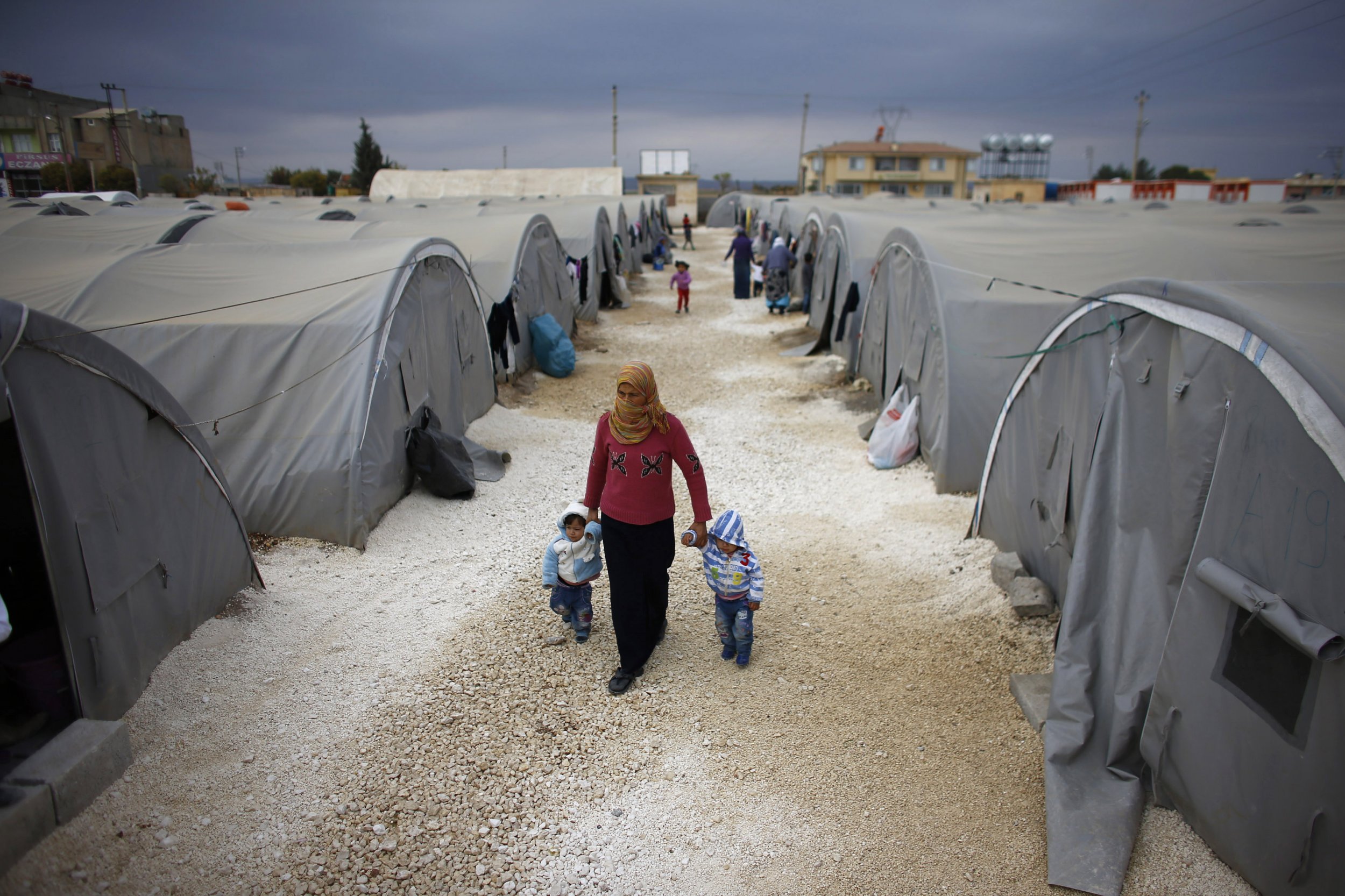 A Kurdish refugee from Syria walks with her children at a refugee camp in Turkey