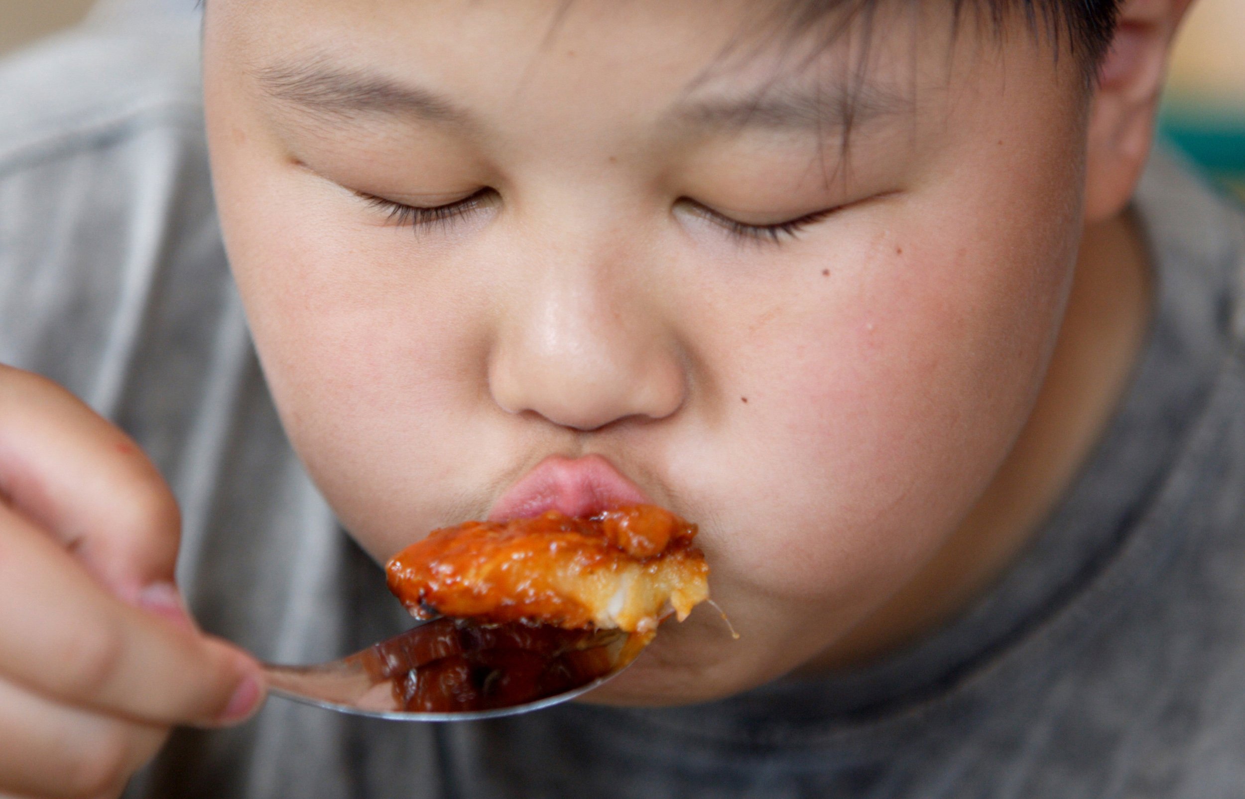 An overweight Chinese boy eats in Beijing.