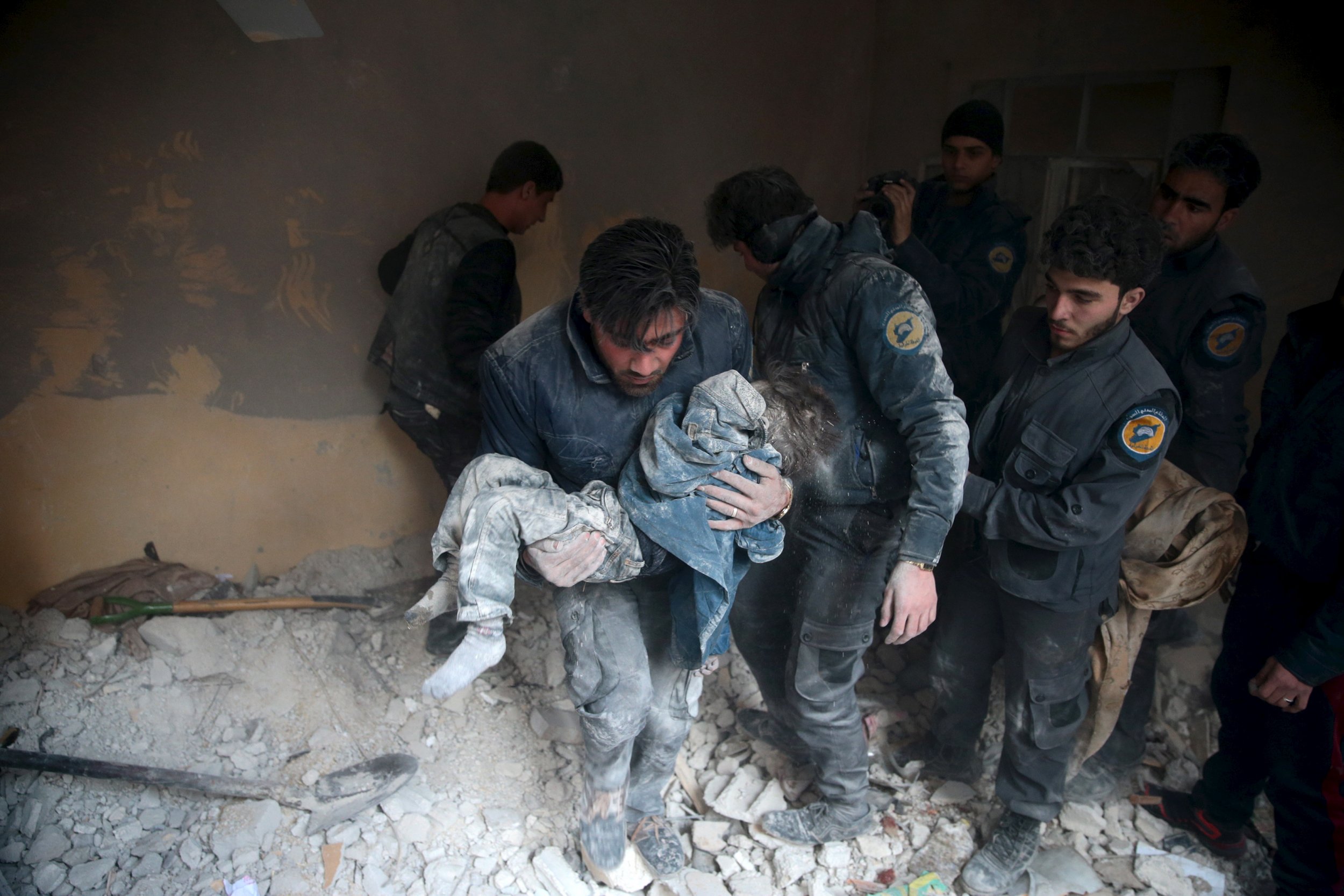 A man carries a child from debris in Damascus after what activists claim was a Russian airstrike.