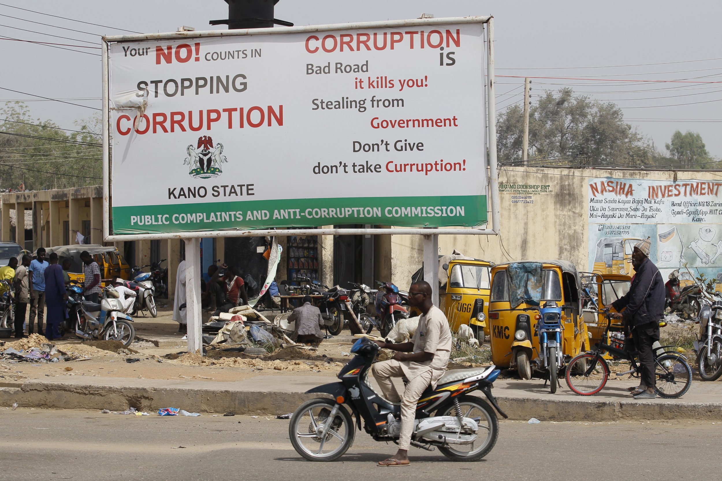 A motorcyclist sits near an anti-corruption sign in Kano, Nigeria.