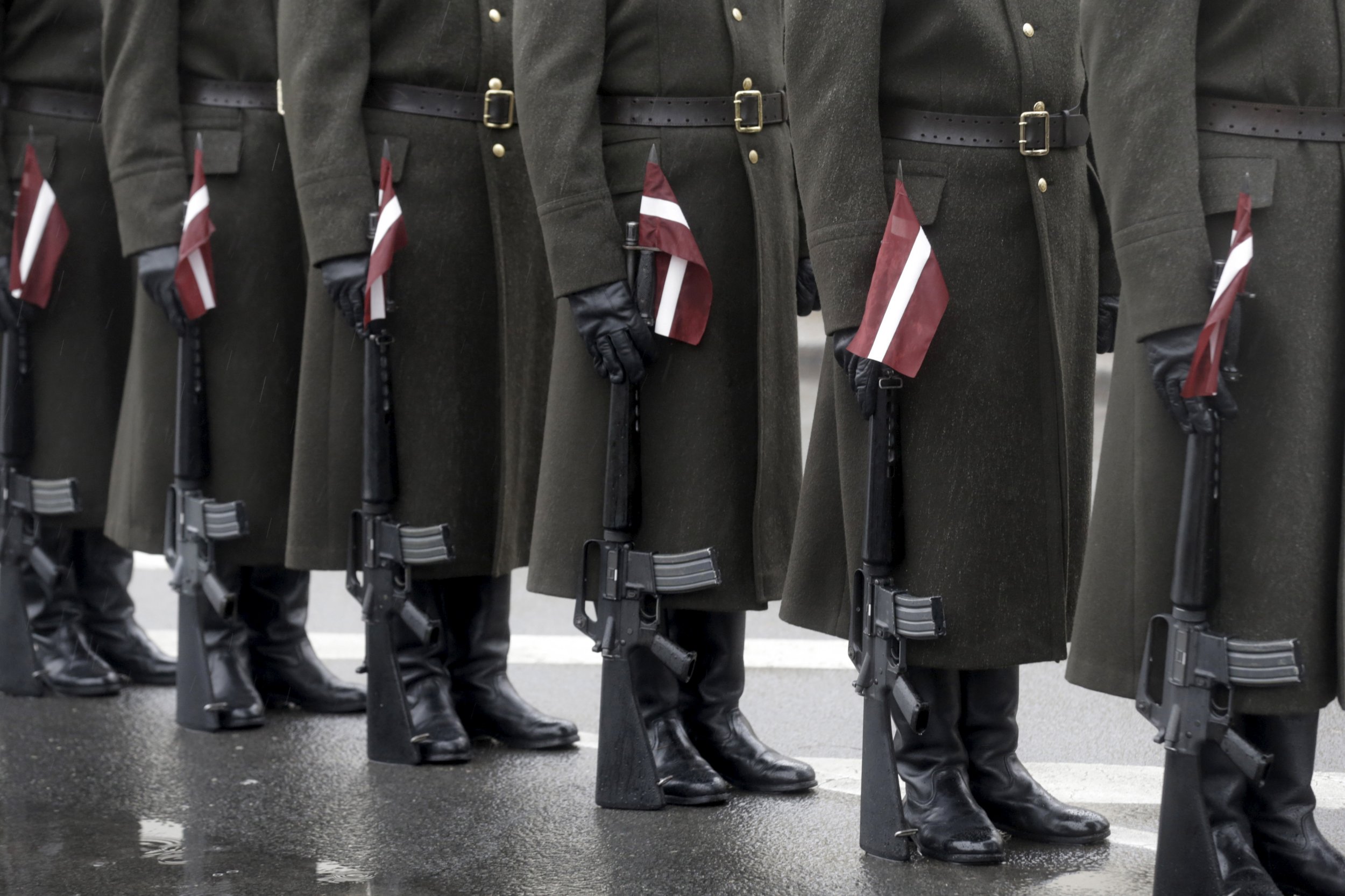 Latvian Soldiers stand to attention with flags at their side