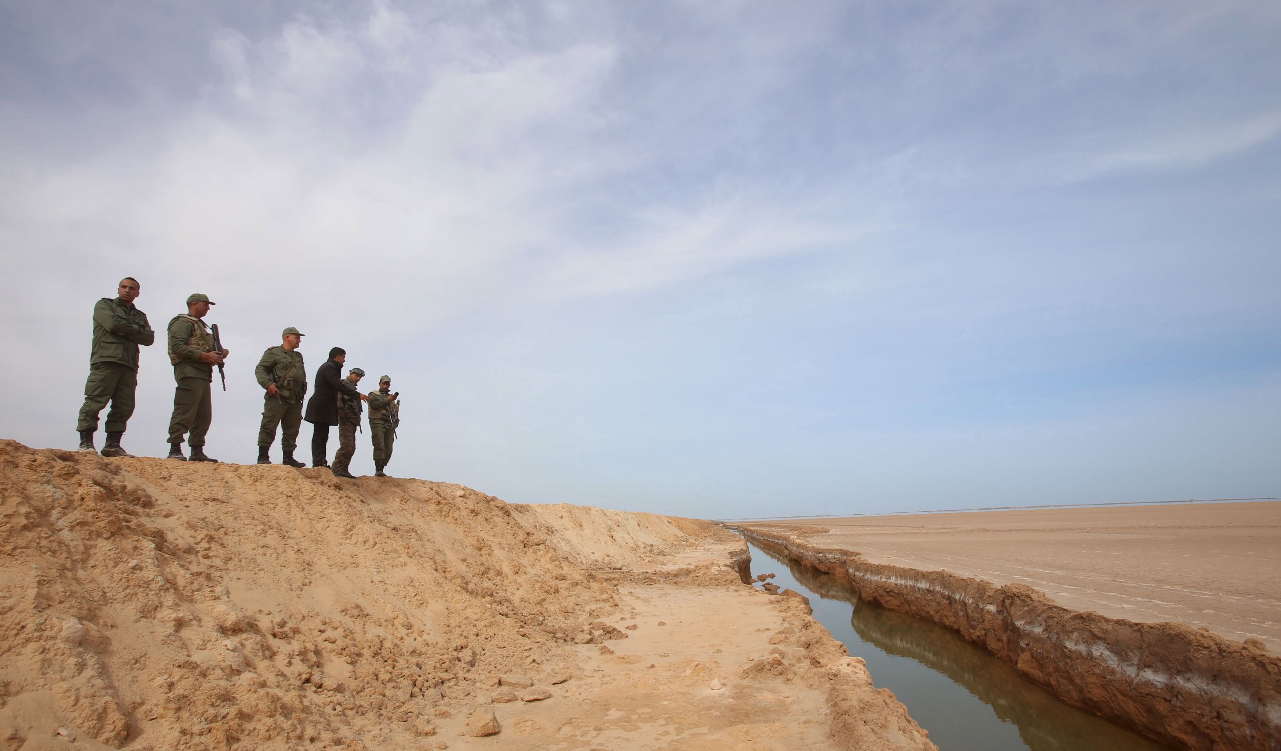 Tunisian soldiers look at the border barrier with Libya.