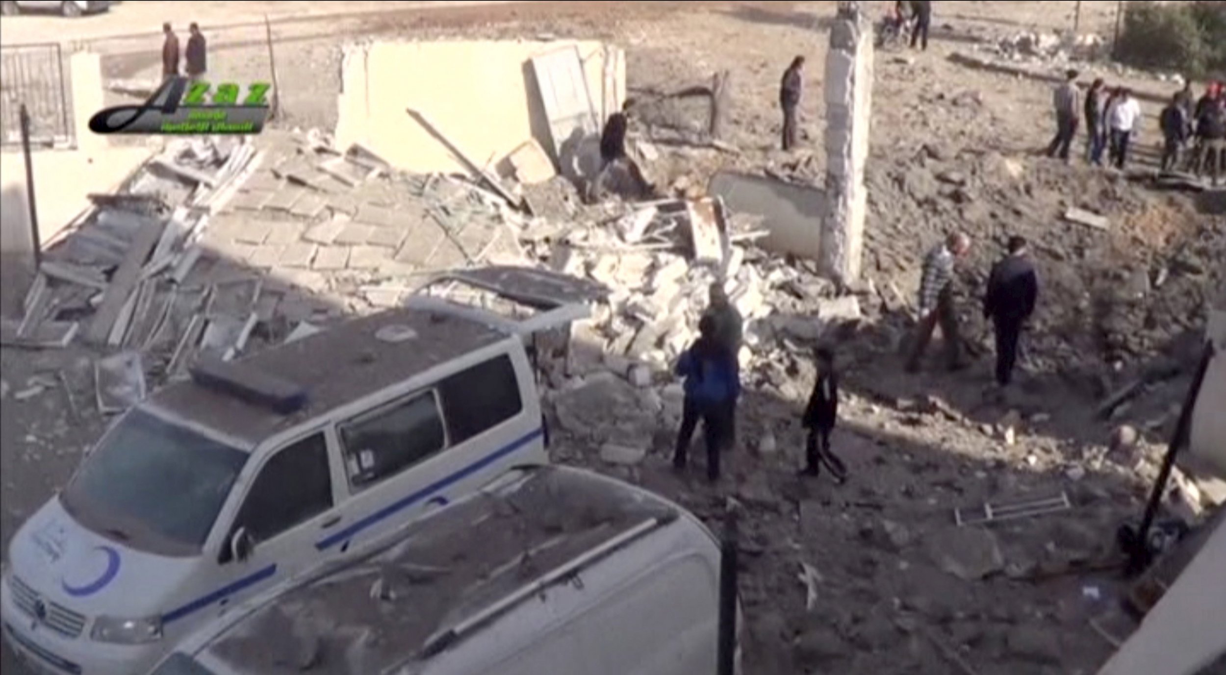 Syrian civilians stand in the rubble of a ruined building