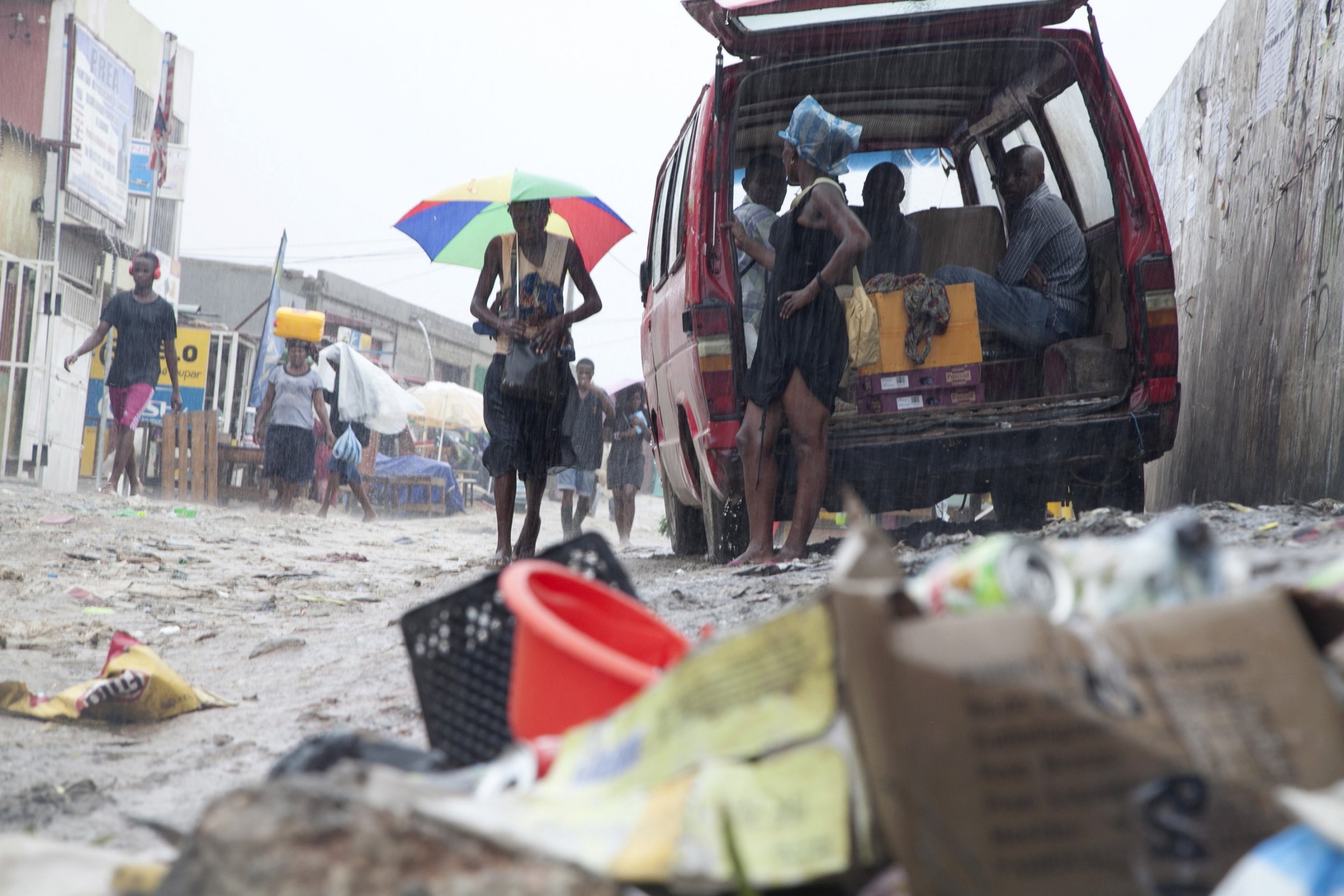 Angola residents walk through a pile of garbage