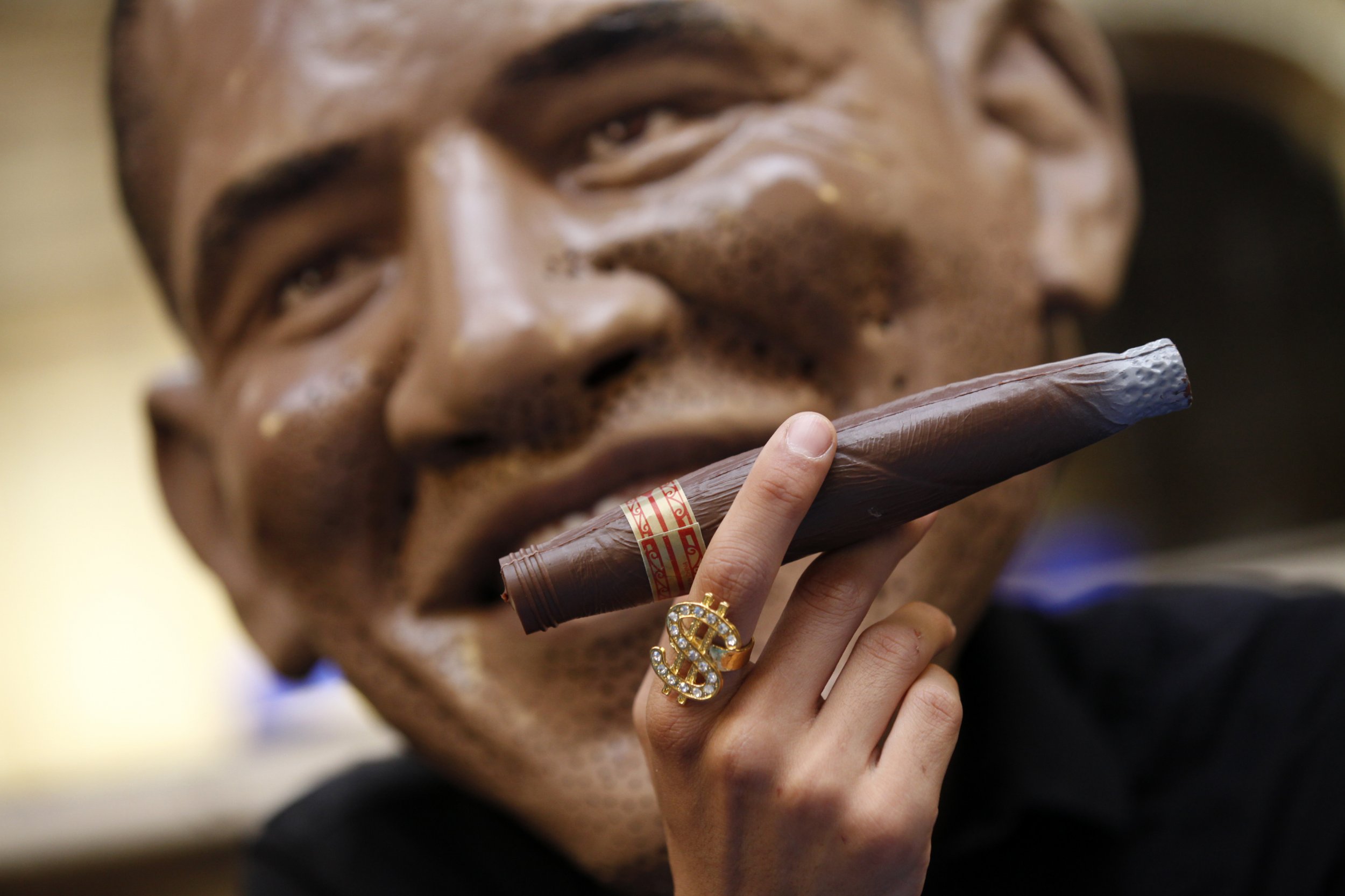 A man with a giant Obama mask smokes a cigar