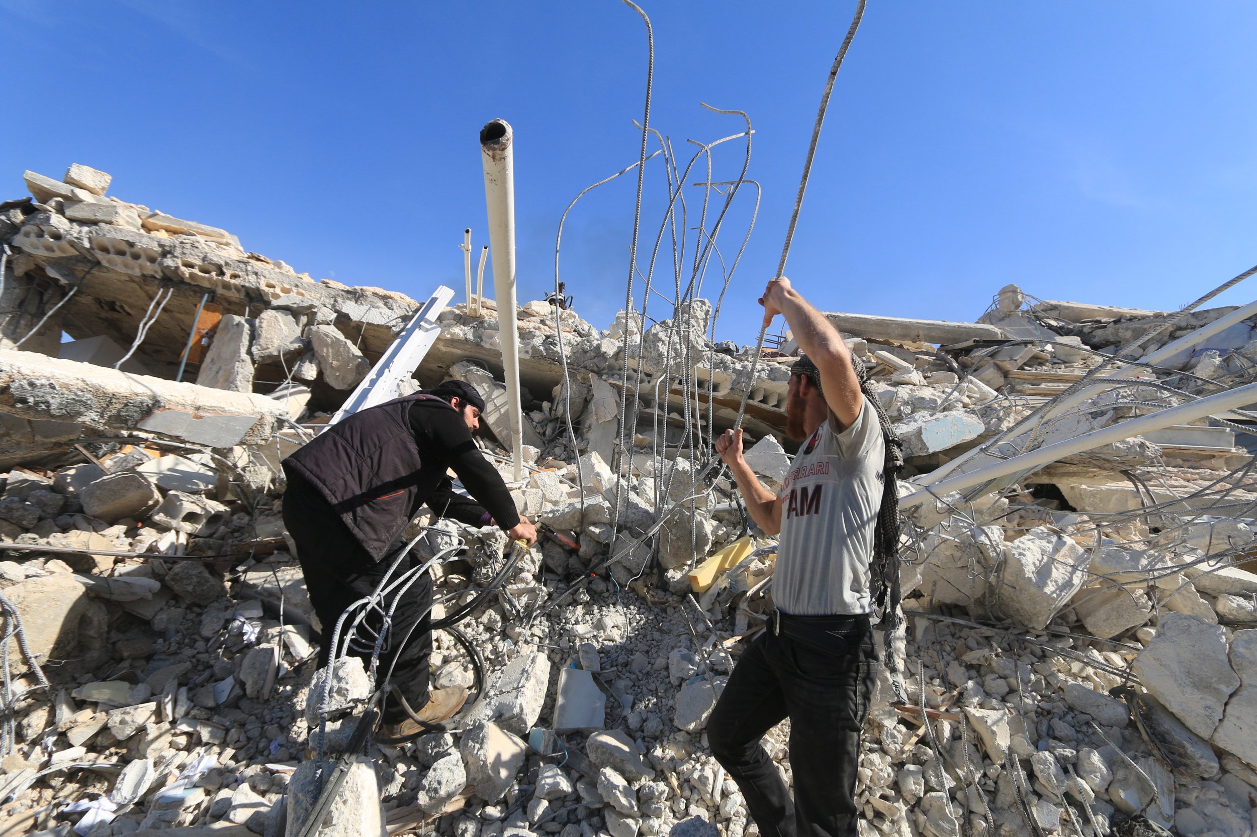 Two men remove rubble at Idlib hospital ruin