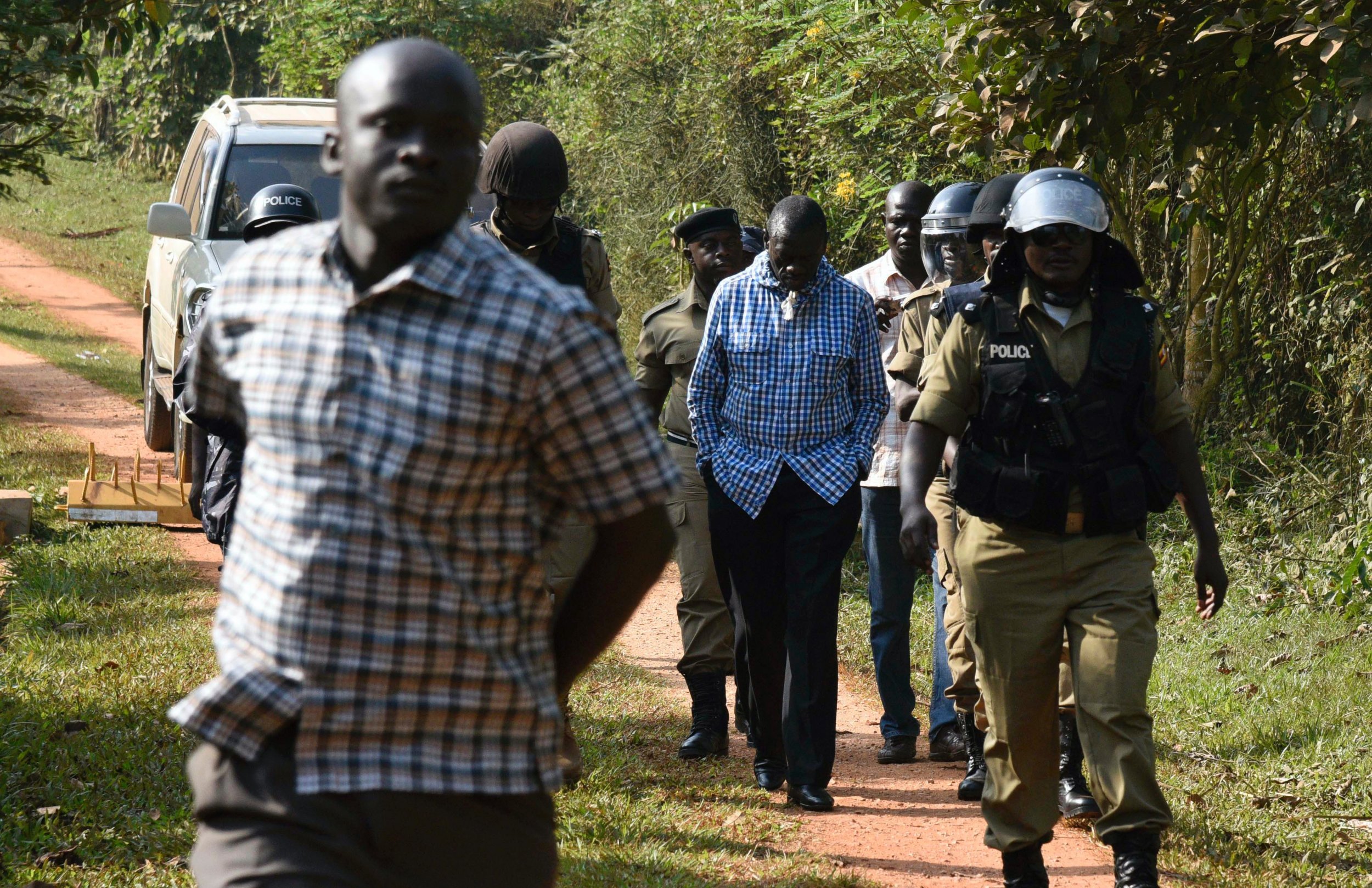 Kizza Besigye is escorted to a police vehicle in Kampala.