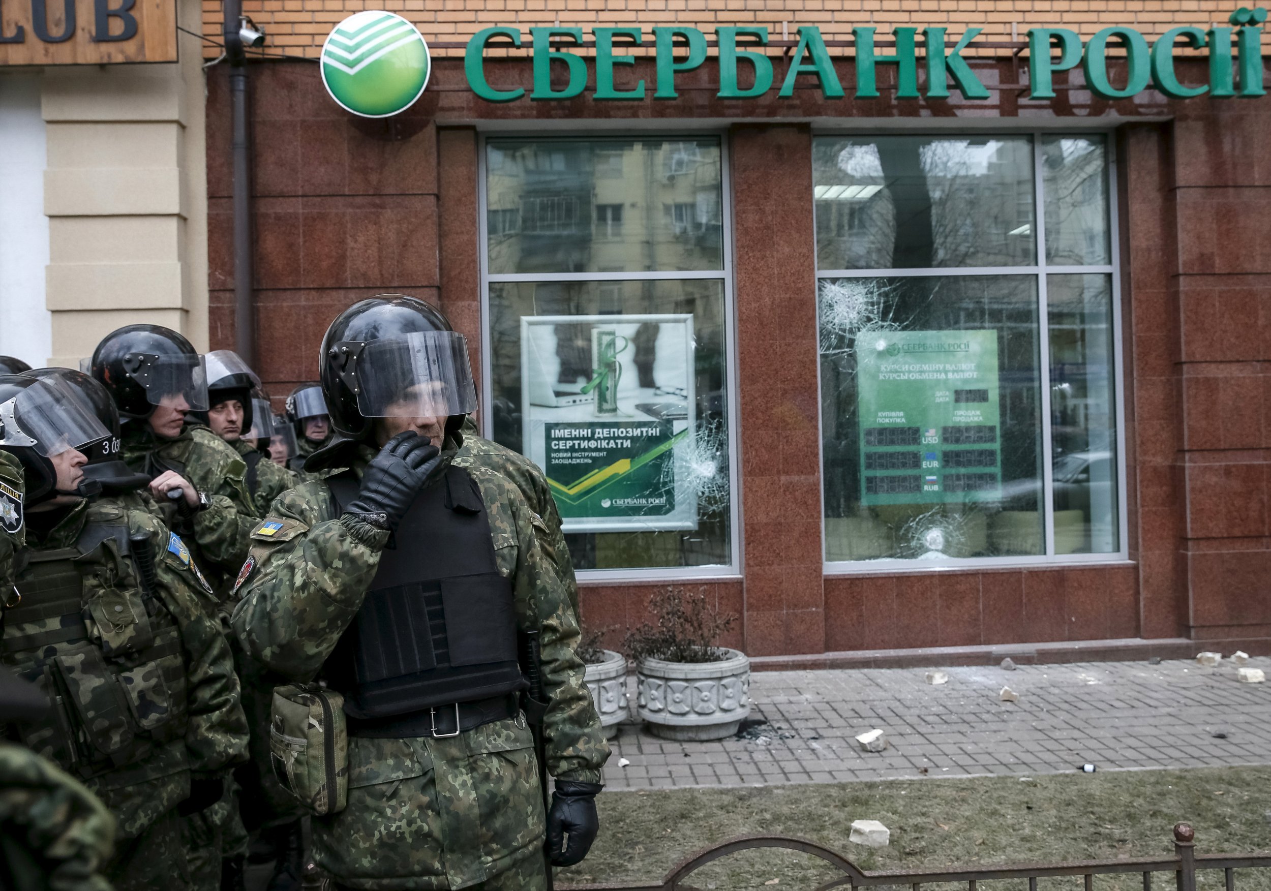 Ukrainian riot police stand in front of vandalised Russian bank