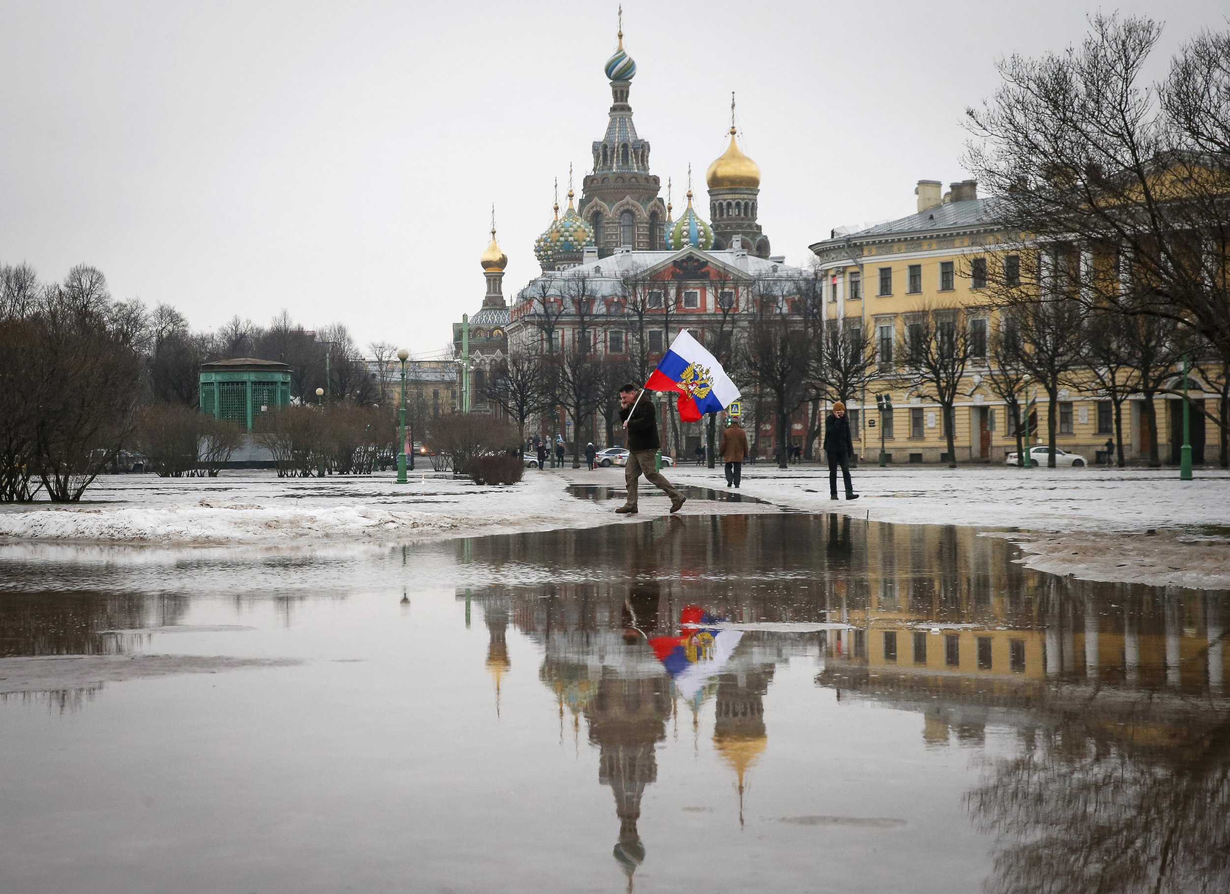 Man walks with a Russian flag in front of an ornate church