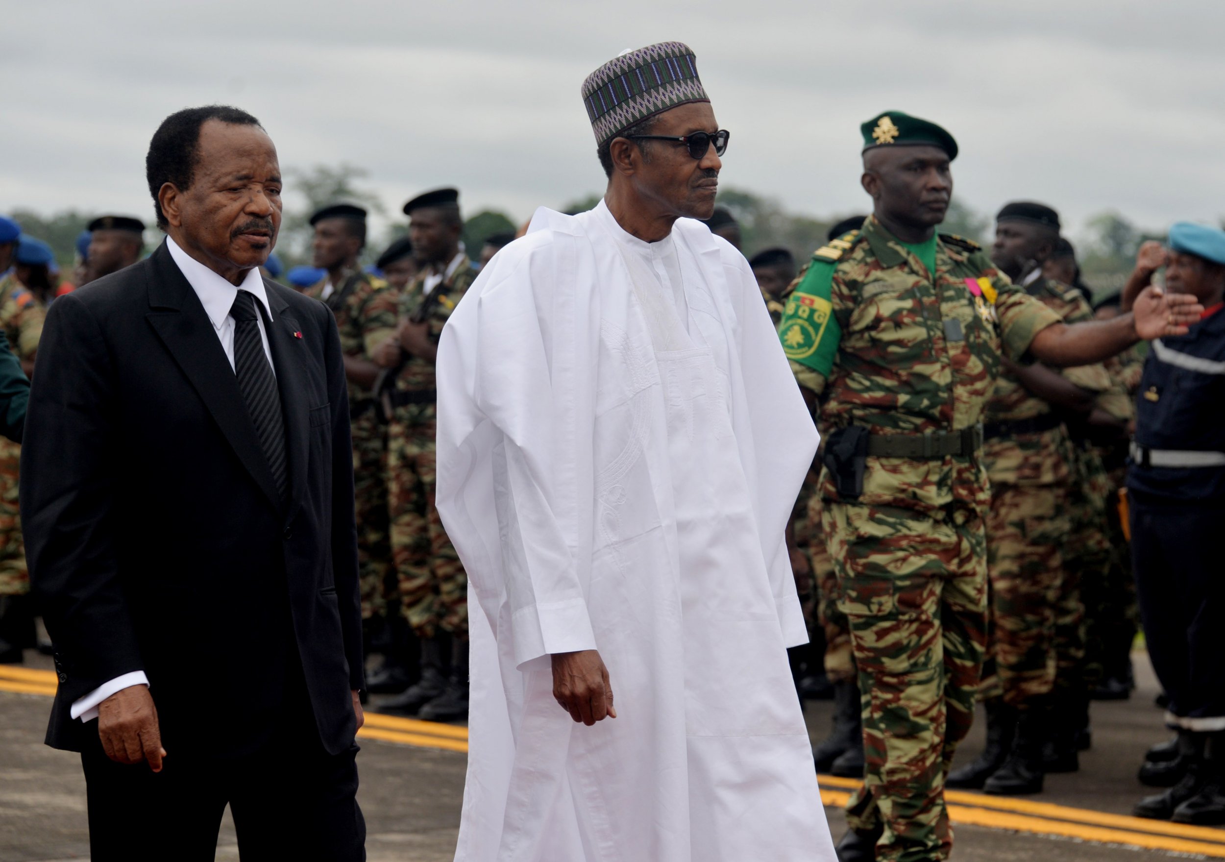 Cameroonian President Paul Biya walks with Nigerian President Muhammadu Buhari.