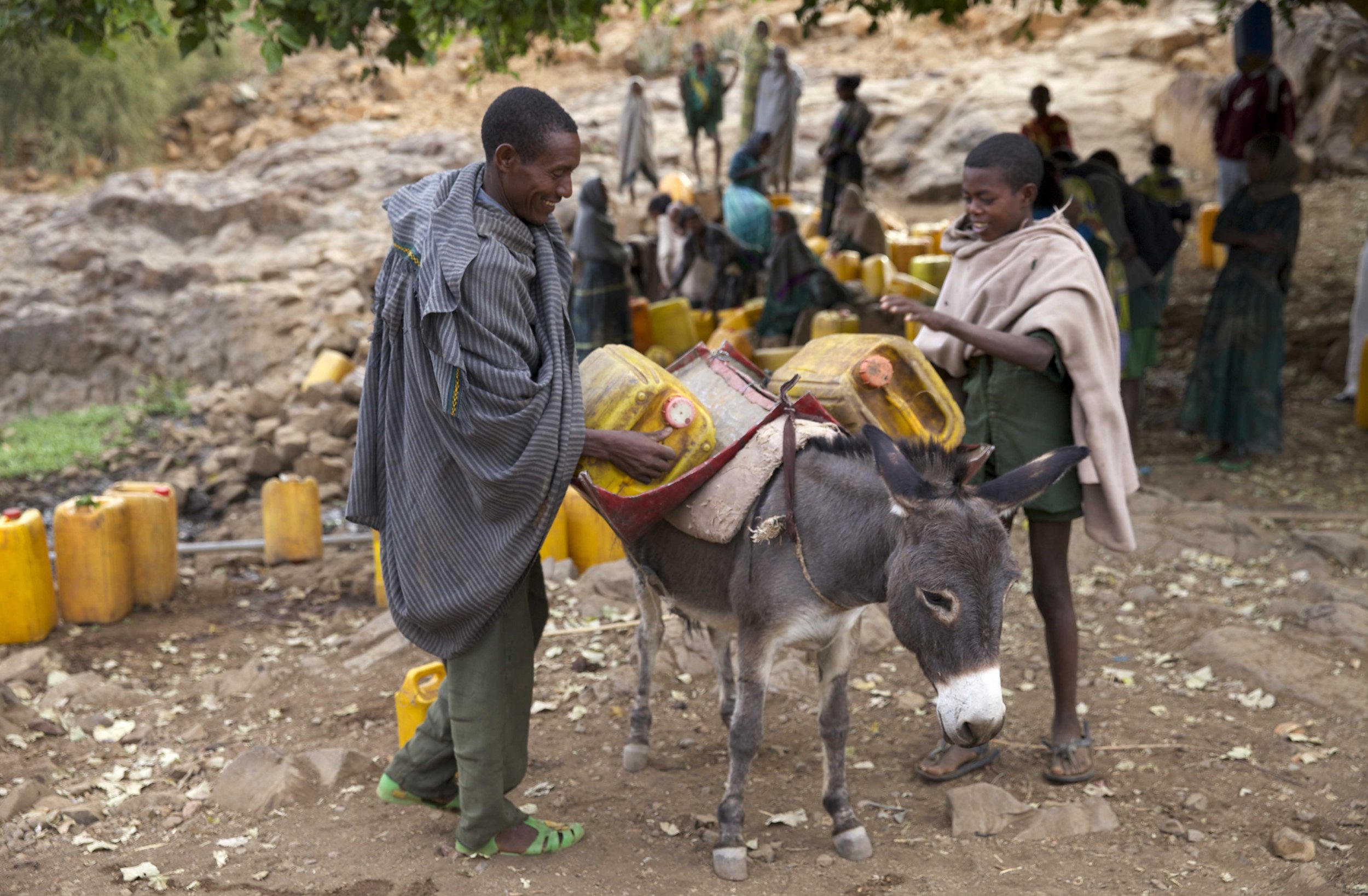Ethiopian people load a donkey with water.