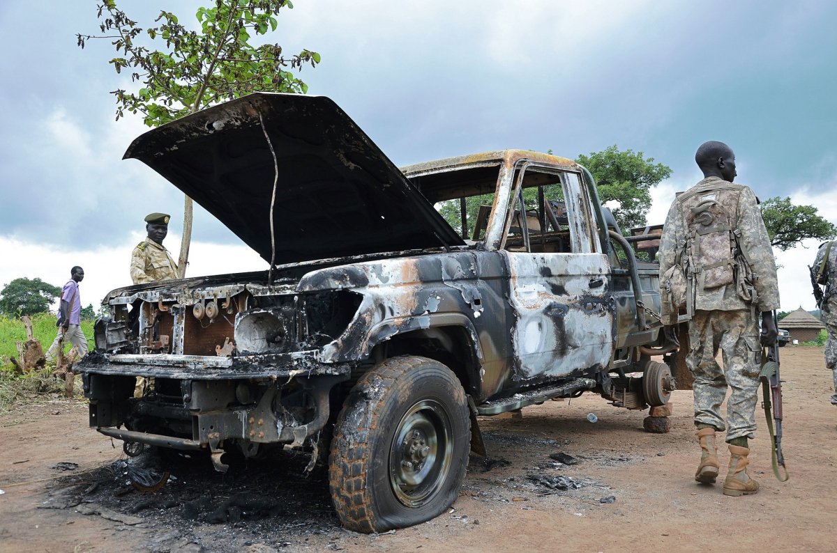 South Sudanese soldiers walk past a burned out car.