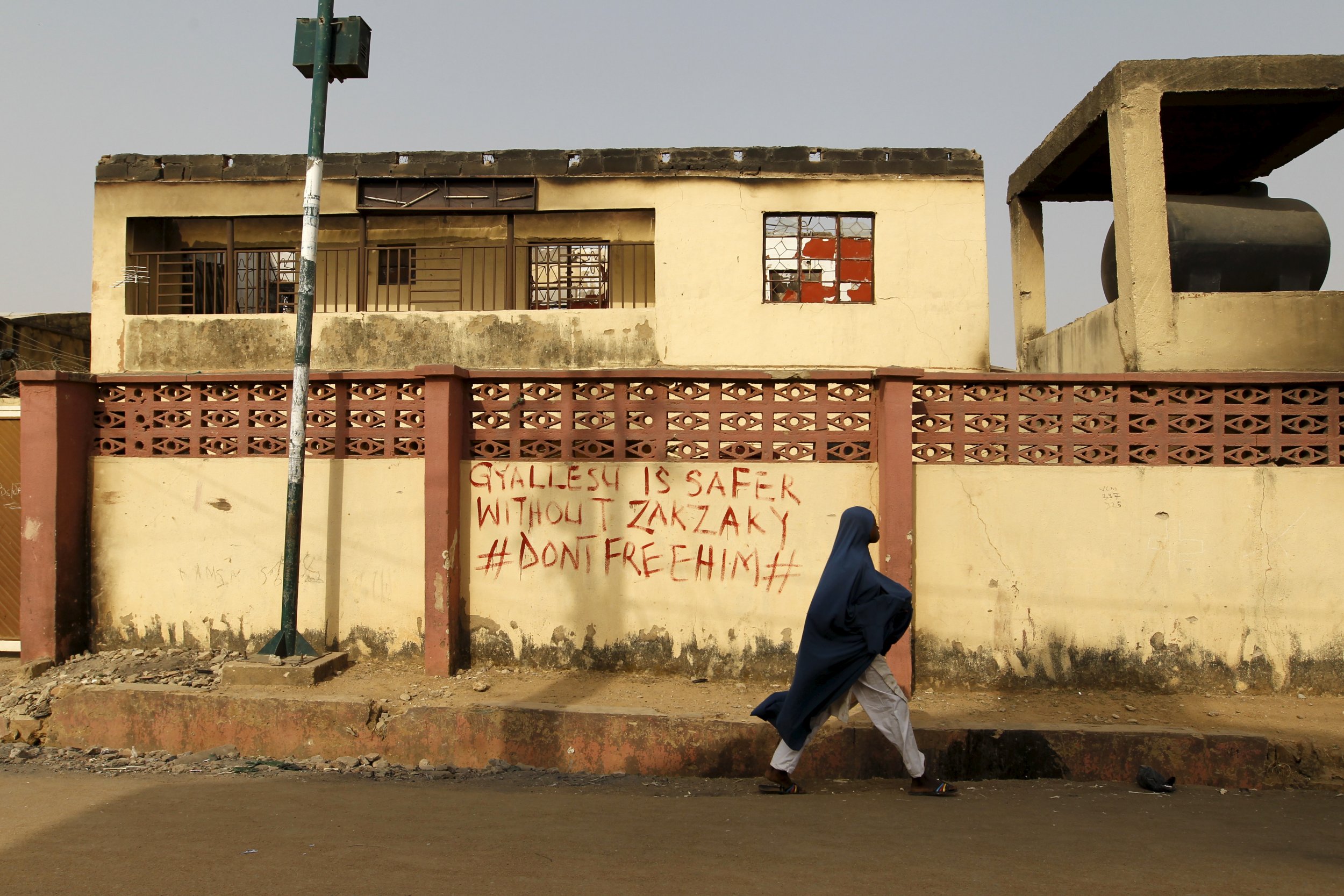 A woman walks past a house destroyed in clashes between Shiites and the army in Zaria, Nigeria.