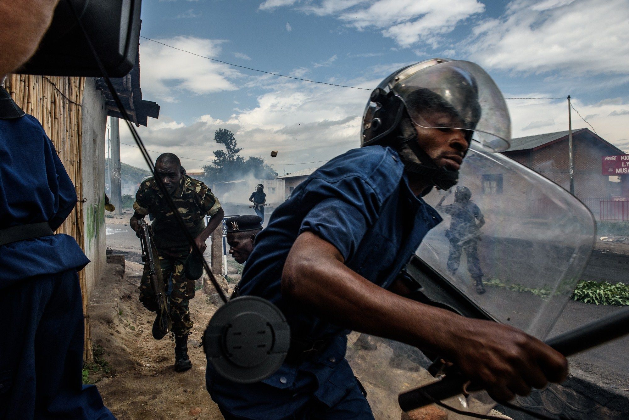 A Burundian police officer runs after protestors in Bujumbura.