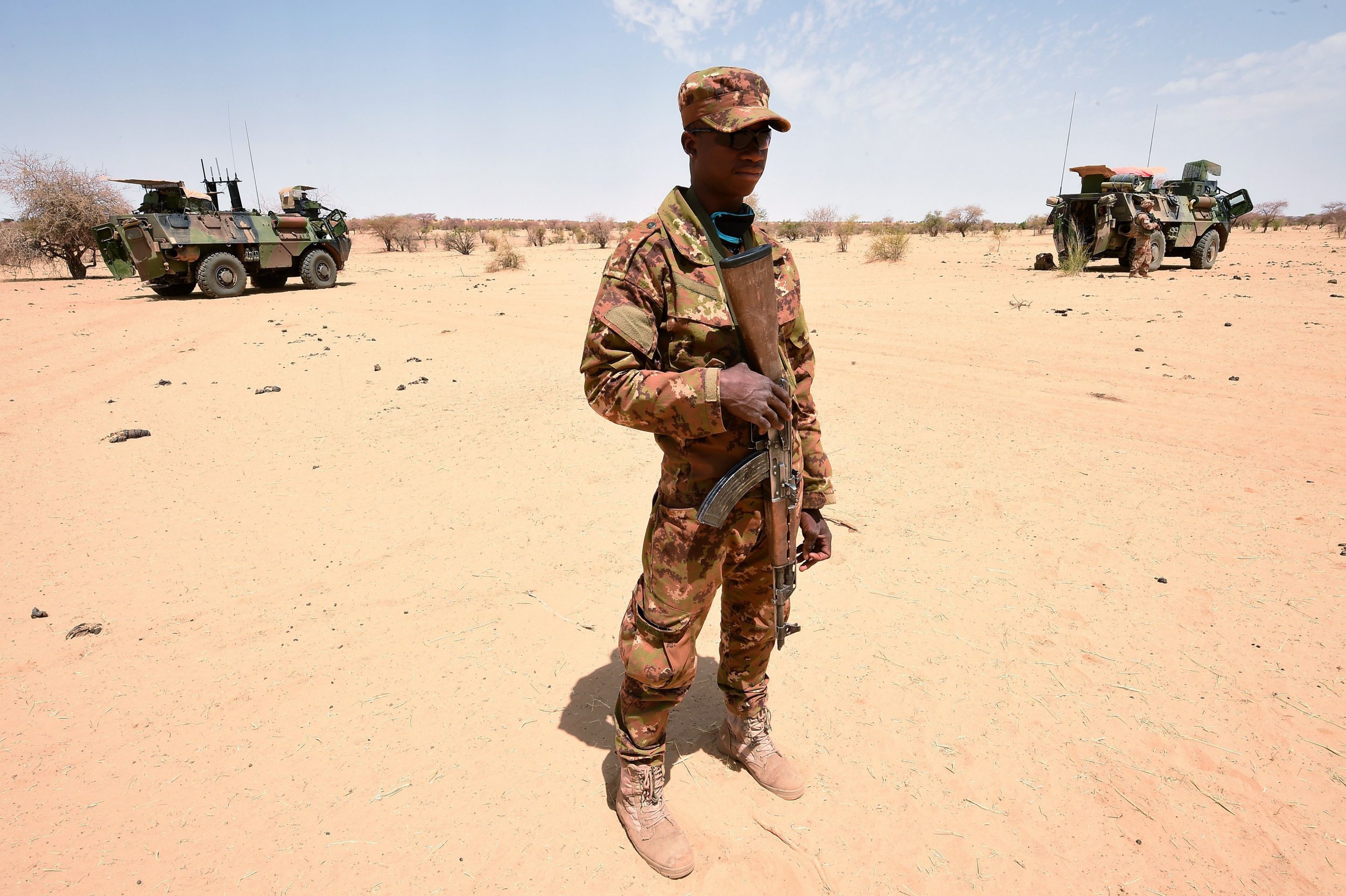 A Malian soldier patrols with French soldiers.