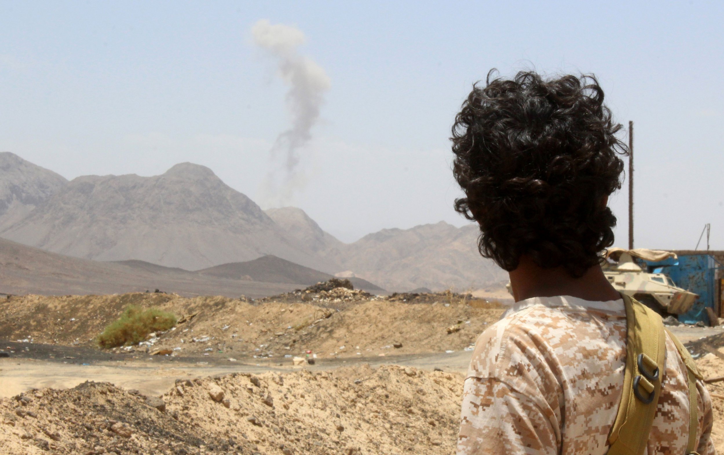 A Yemeni fighter loyal to the exiled president looks at rising smoke.