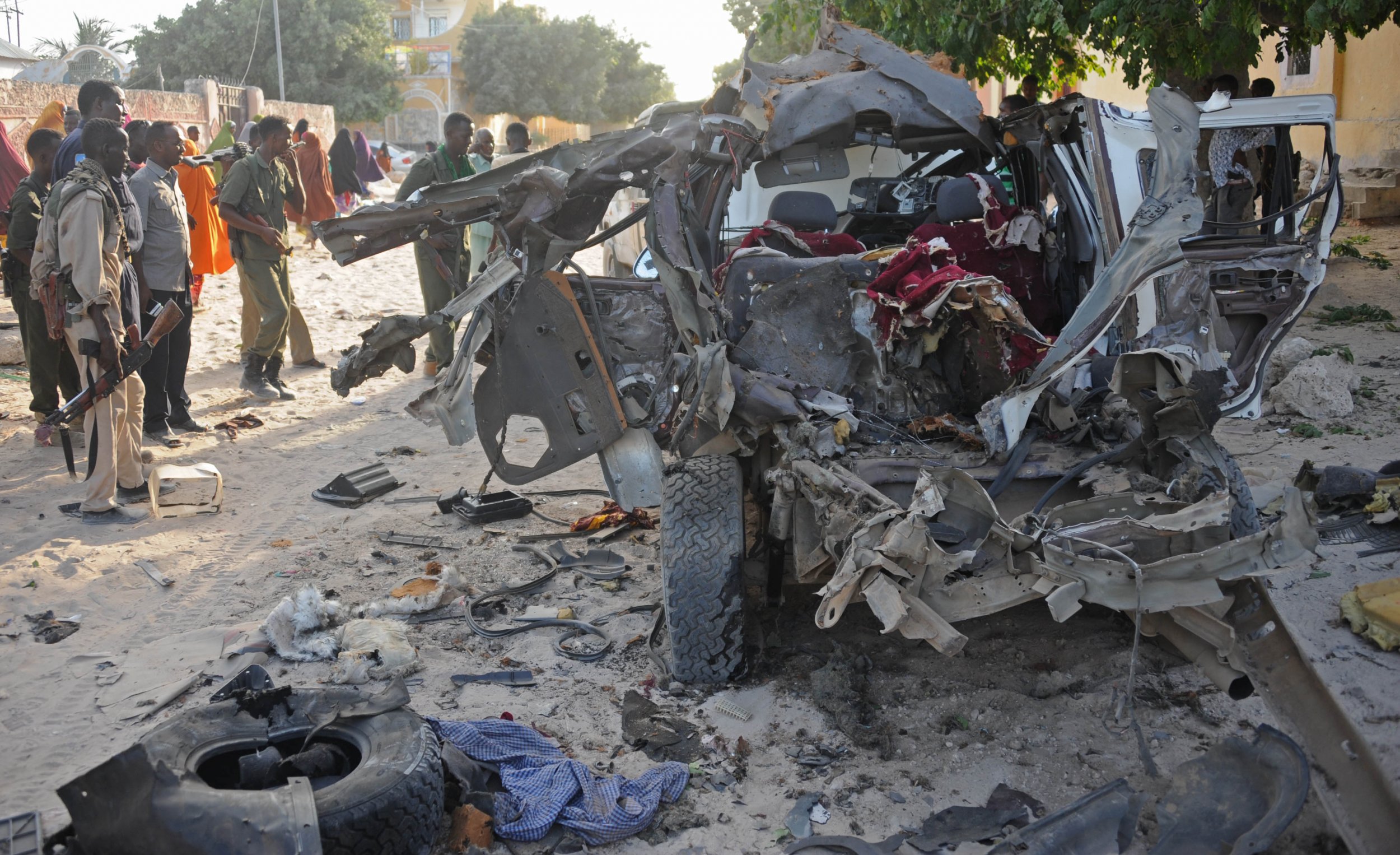 Somali soldiers and residents look at the site of an Al-Shabab car bomb in Mogadishu.