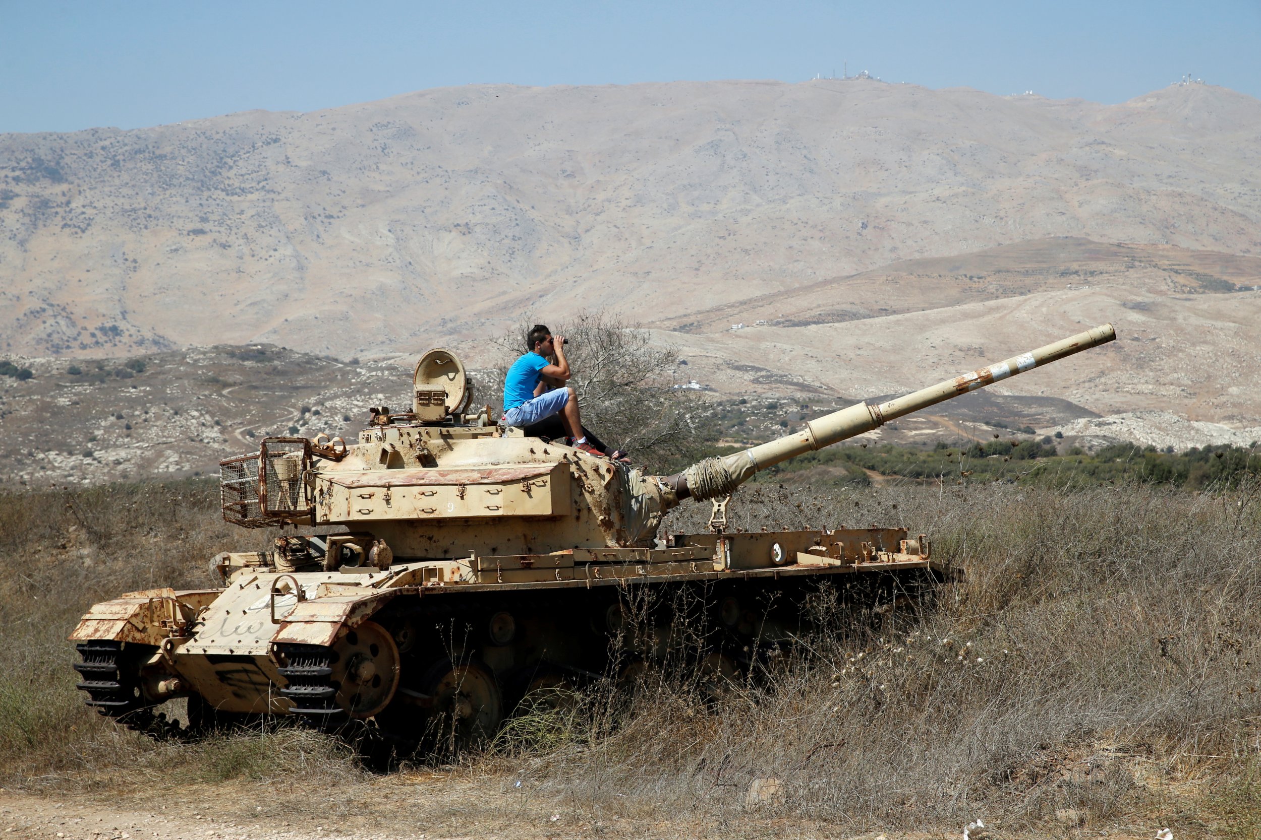 A man on a tank watching Syrian fighting