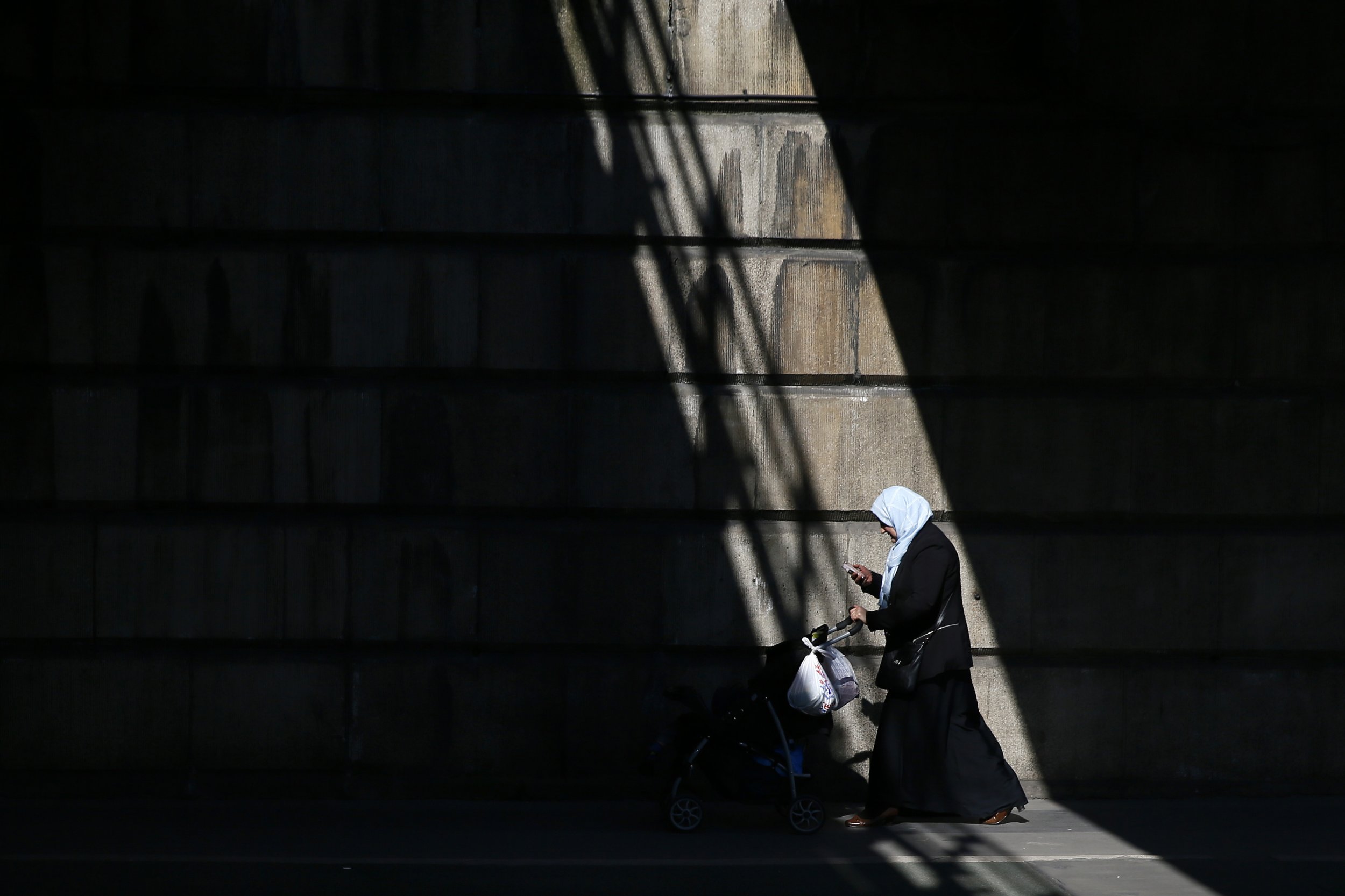 A Muslim woman pushes a pushchair