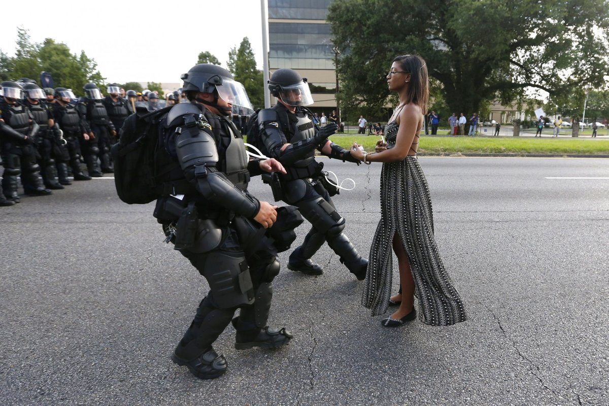 A protester stands before three police officers