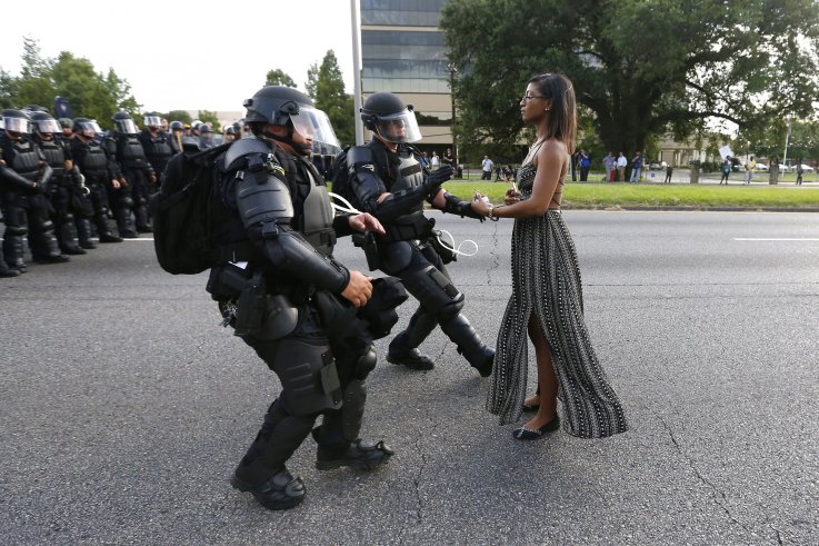 A protester stands before three police officers A protester stands before three police officers