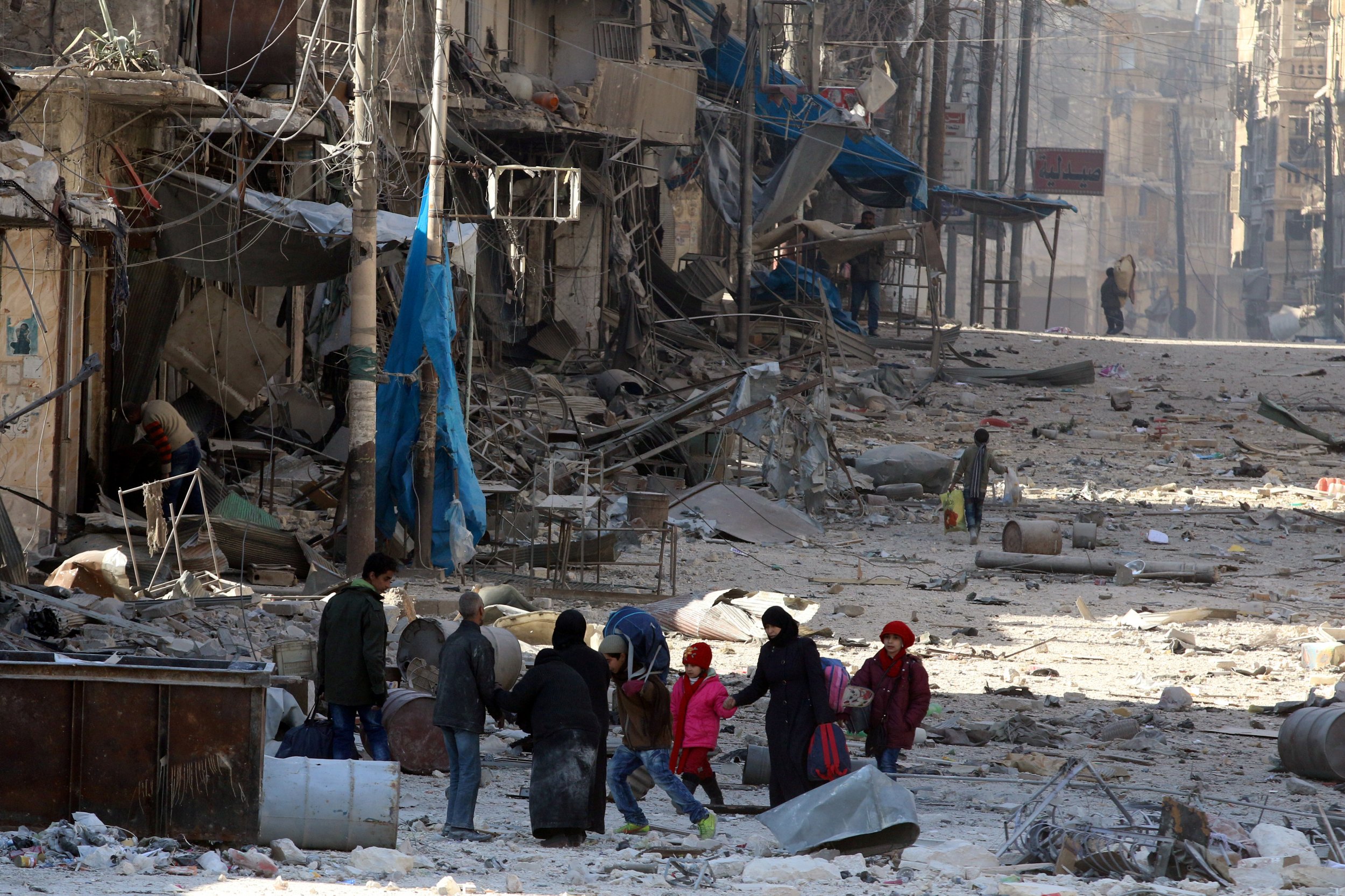 Syrians walk over rubble in Aleppo