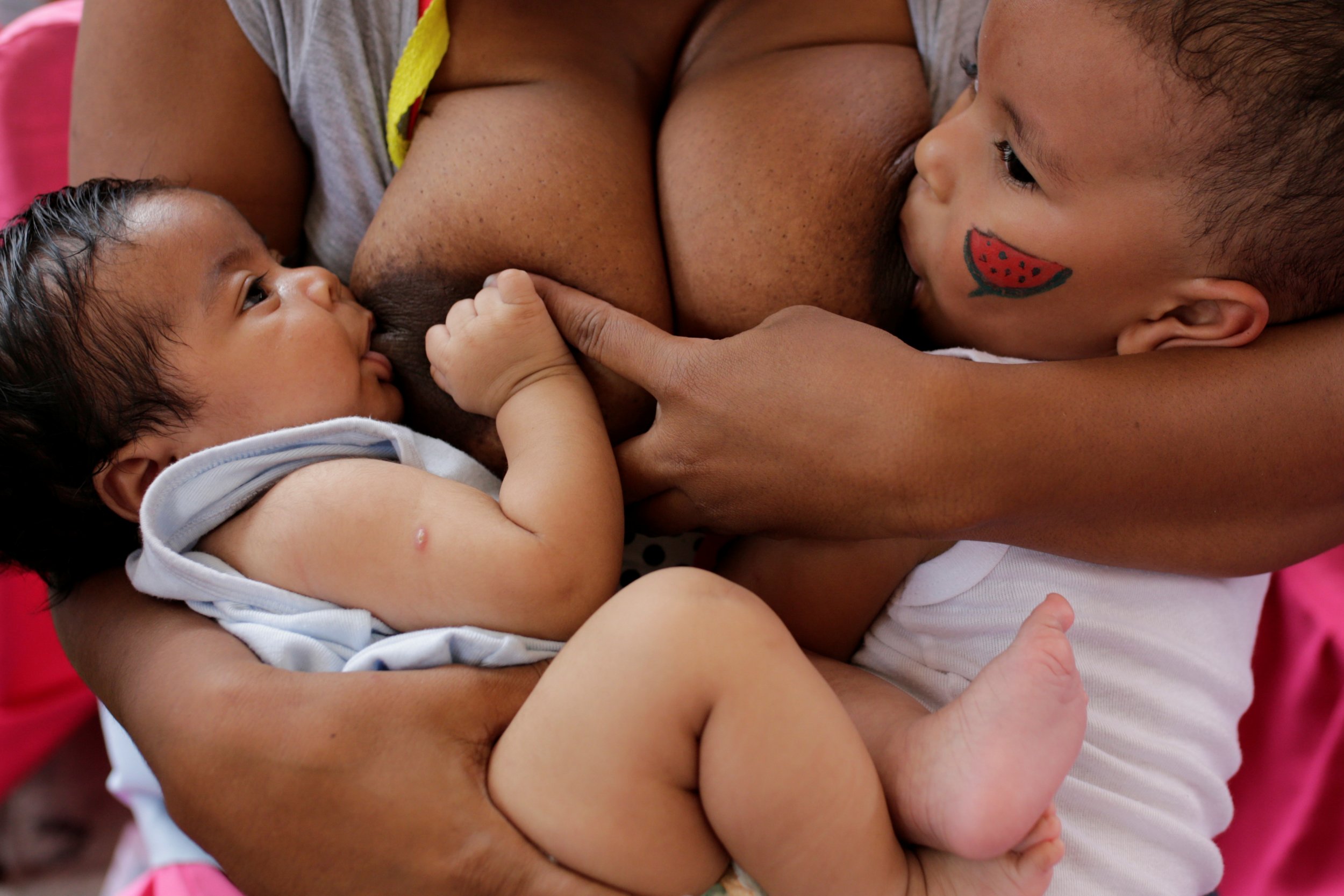 A woman breast-feeds her babies as part of the celebration for World Breast...